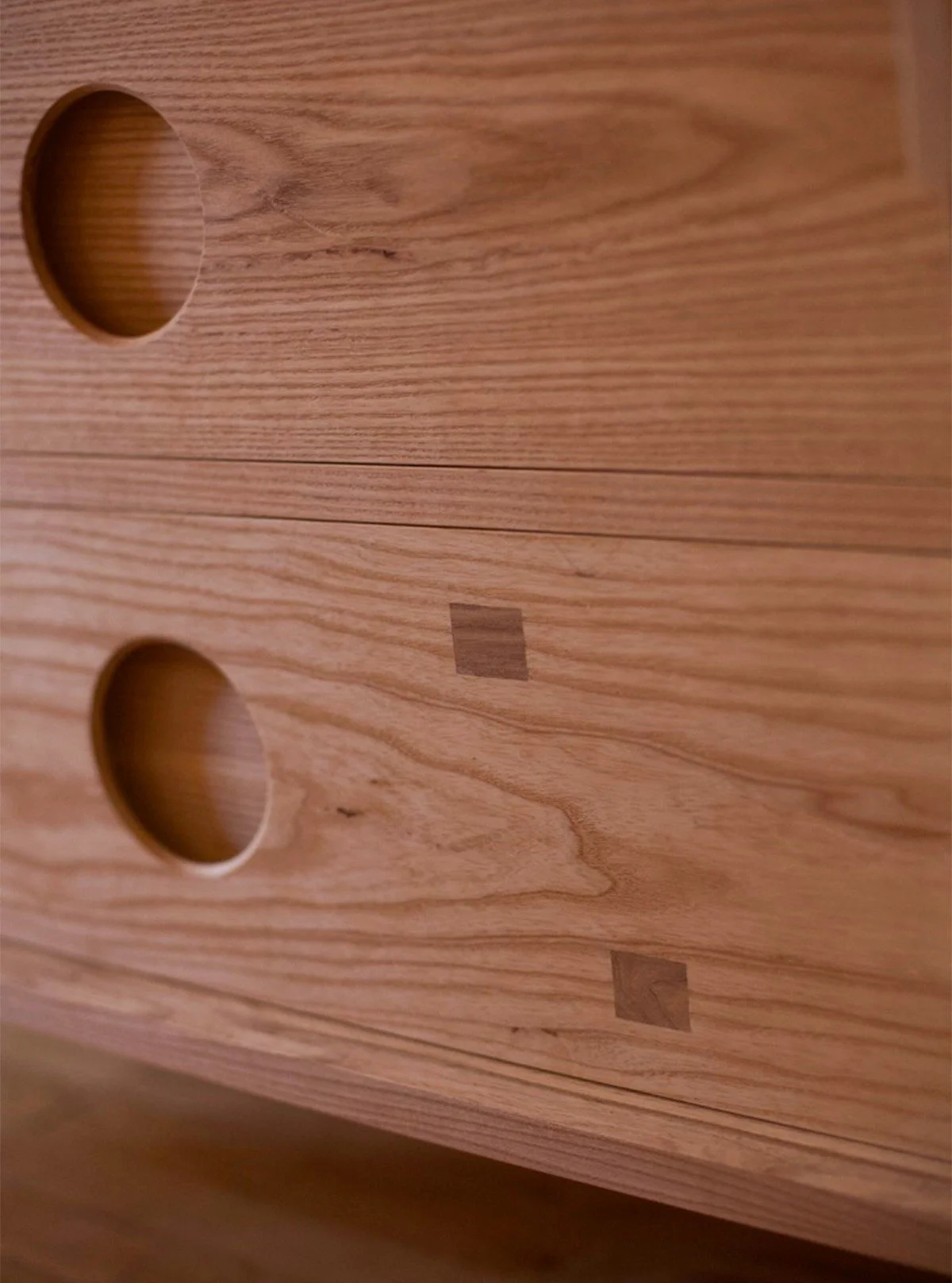 Nearly every design choice on this cabinet was a function of the sliding doors. 

The drawer pulls are created by laminating ash that has a rabbeted circle cut into it over the dovetailed drawer face. This design allows for the doors to slide over th