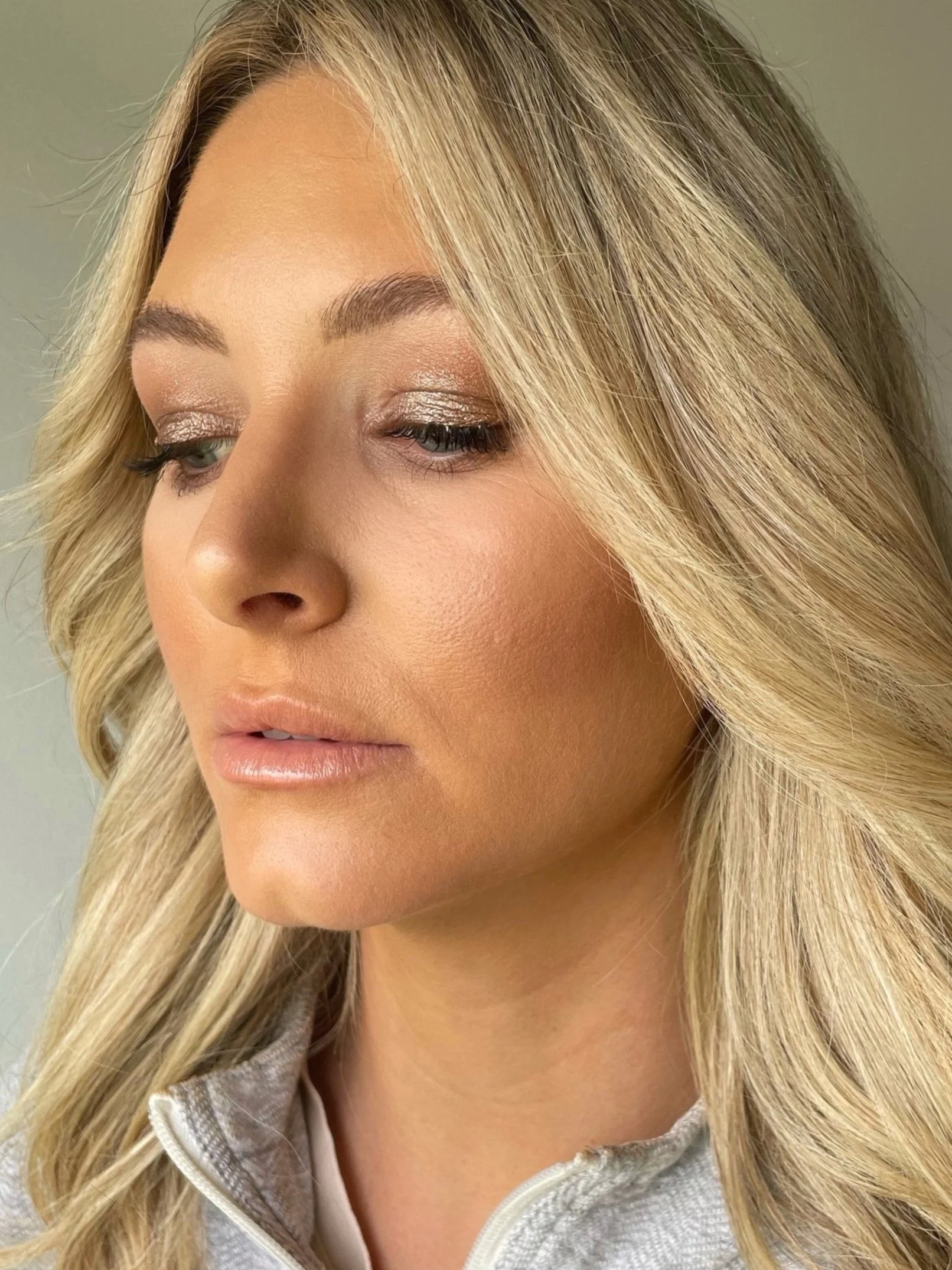 Woman with blonde hair and natural makeup looking down