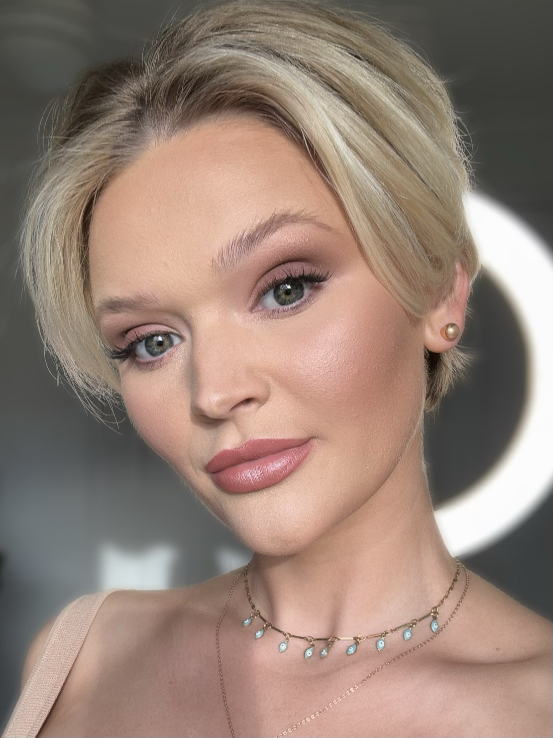 Woman with blonde hair, wearing makeup and jewelry, close-up portrait.