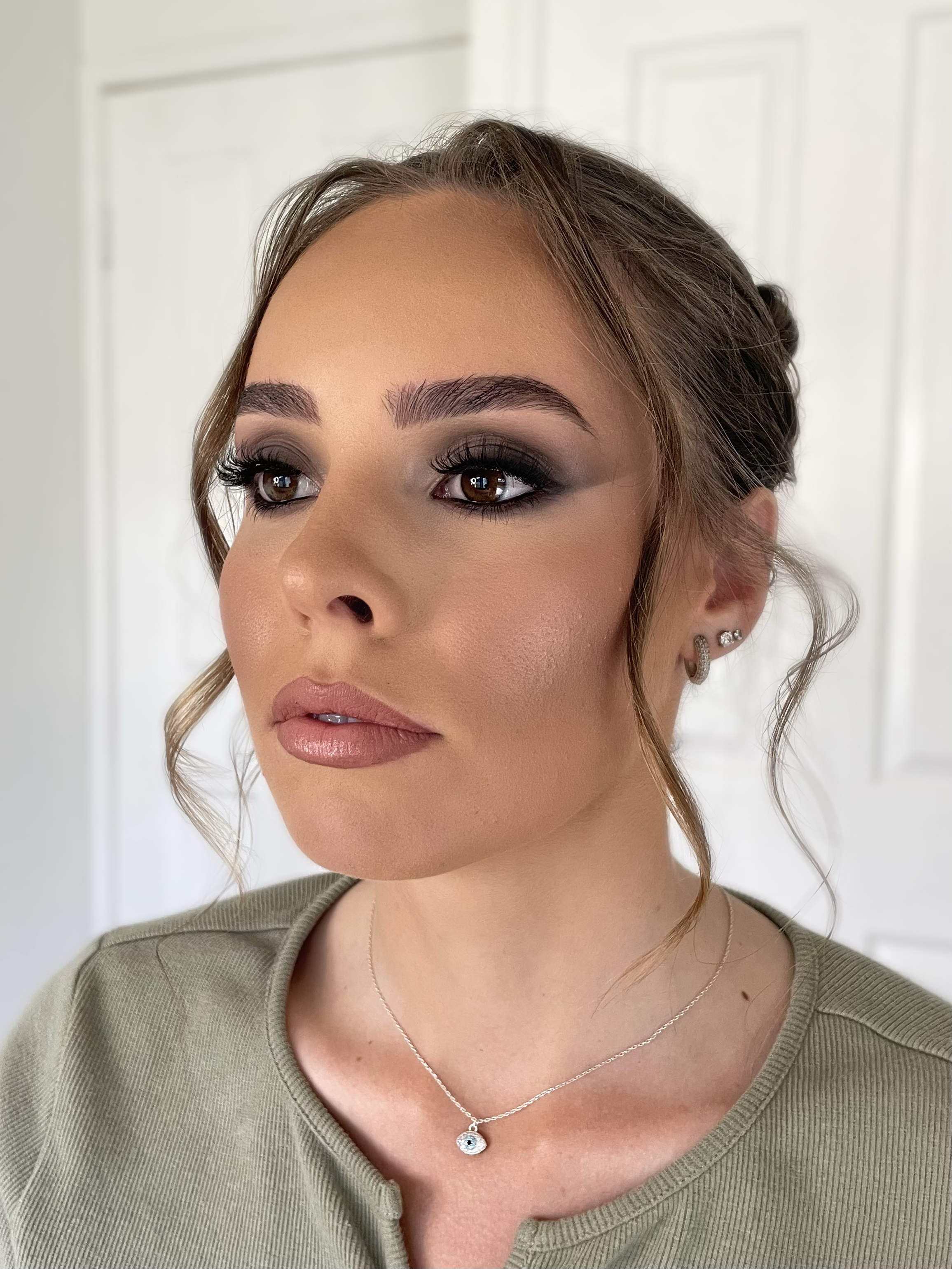 Woman with smokey eye makeup, wearing green top and necklace