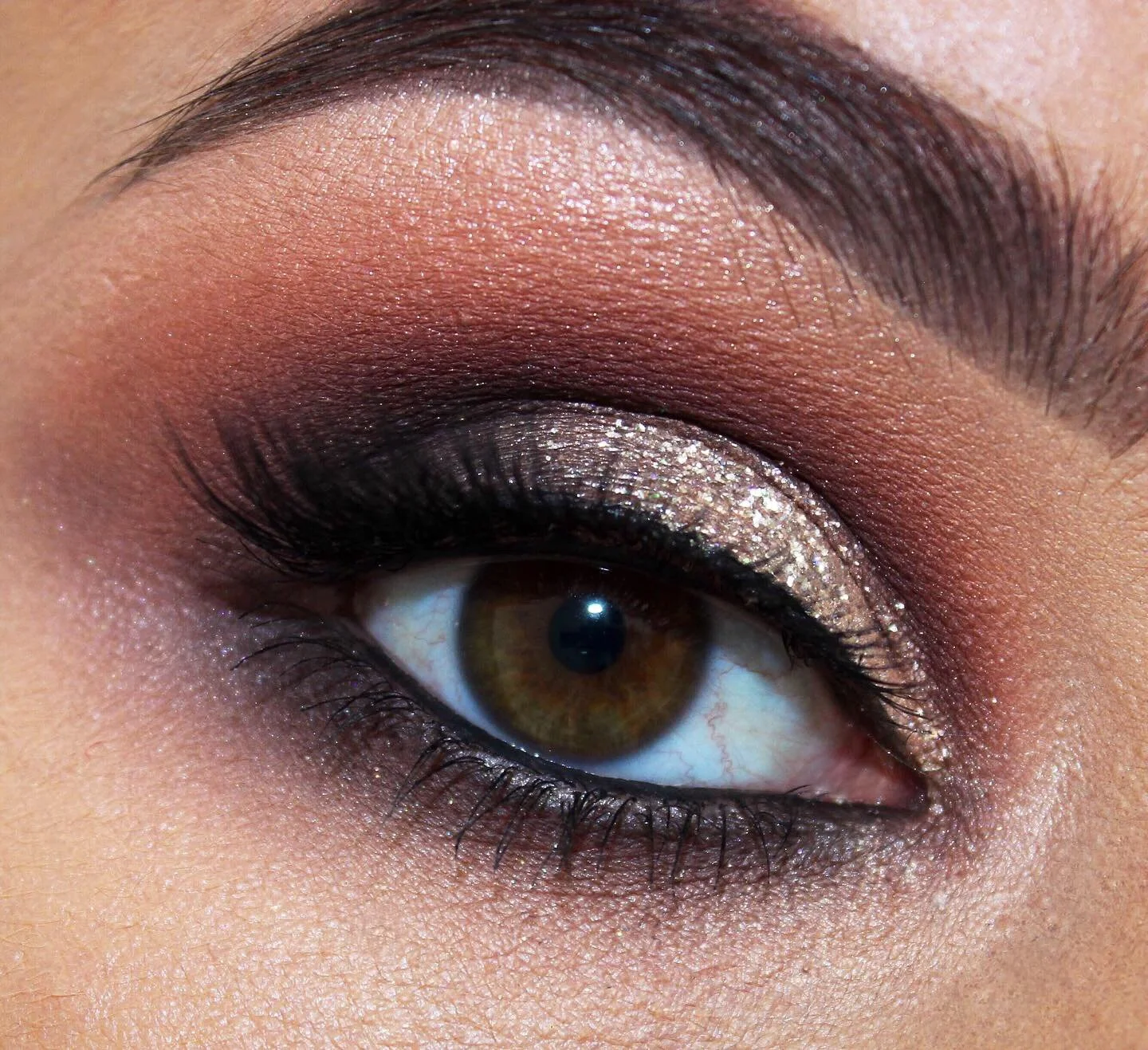 Close-up of an eye with glitter eyeshadow and dark eyeliner.