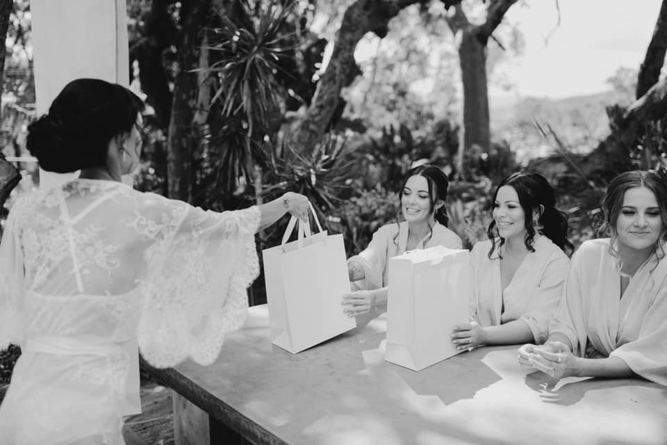 Bride giving gift bags to bridesmaids at outdoor table