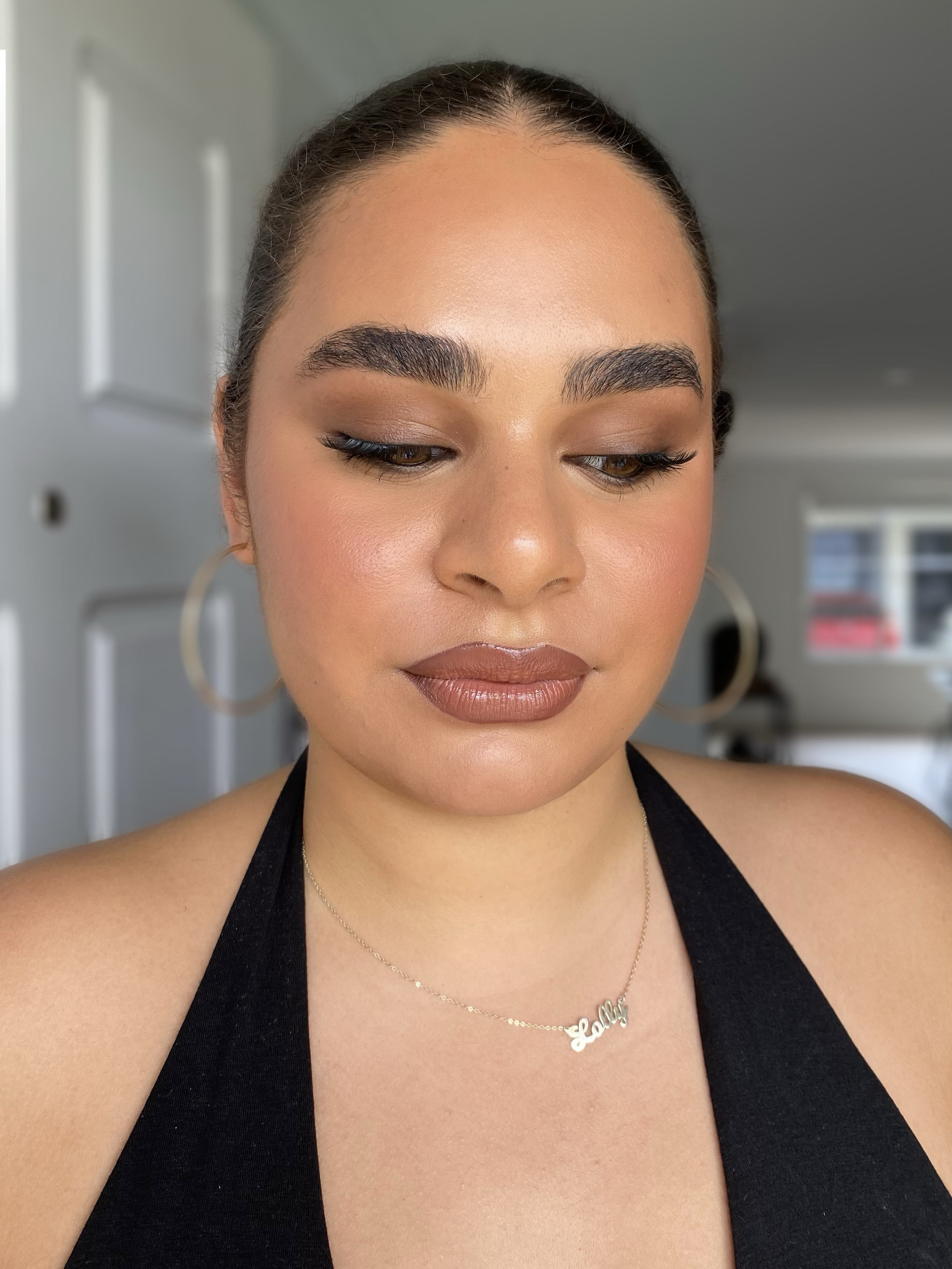 Person with hoop earrings and necklace, wearing makeup with closed eyes.