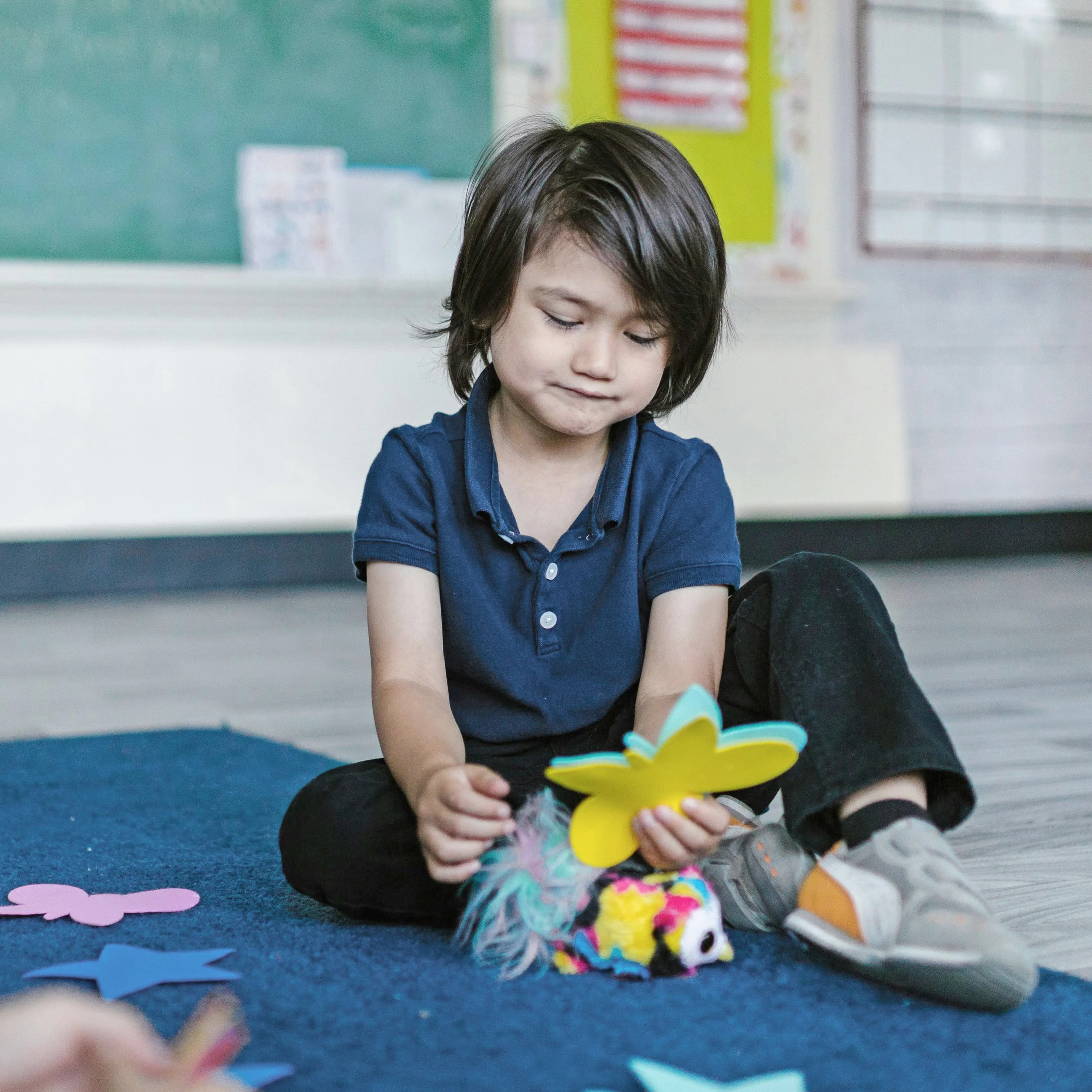 Young boy playing with foam butterfly shapes while sitting on the floor