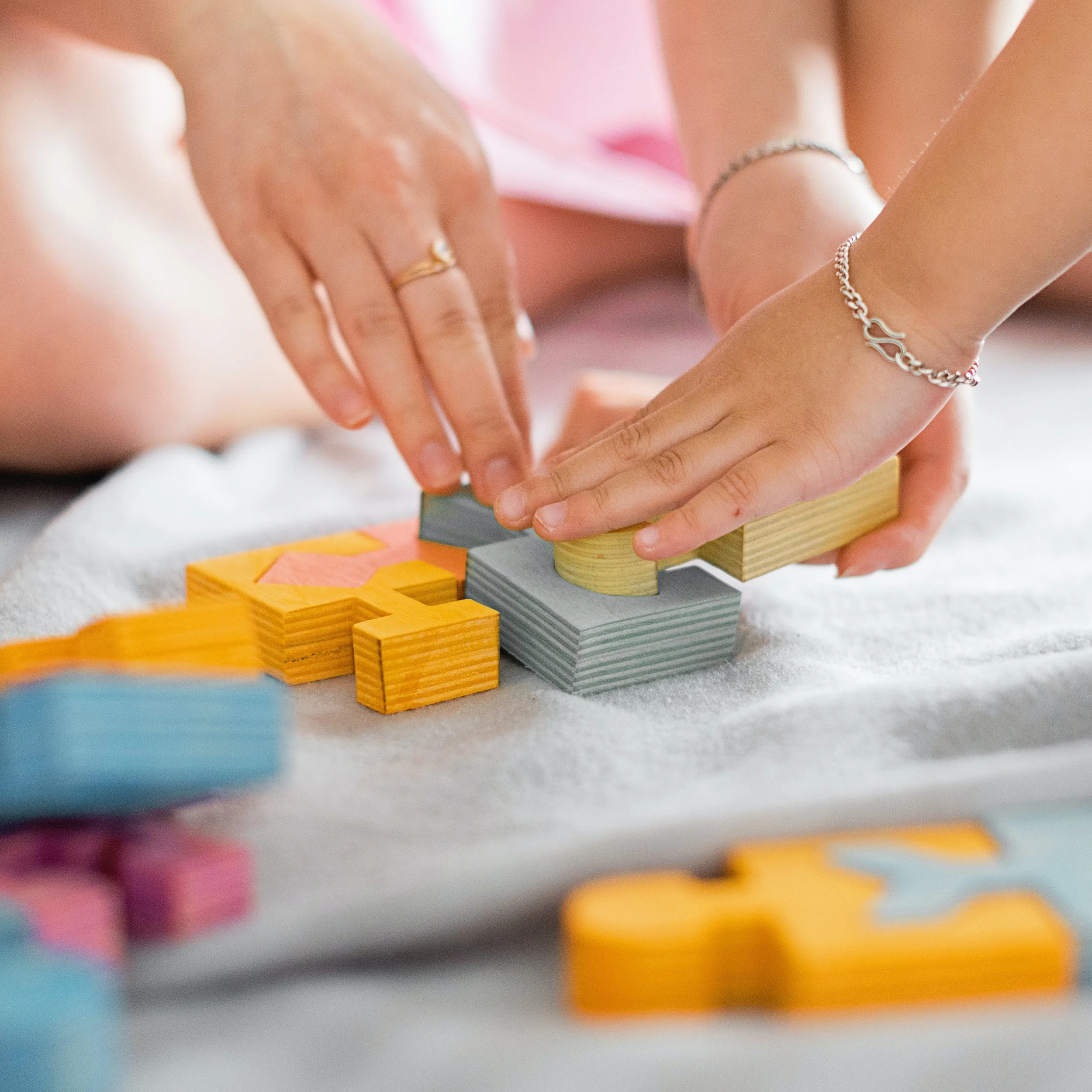 A mother and child playing with wood interlocking blocks