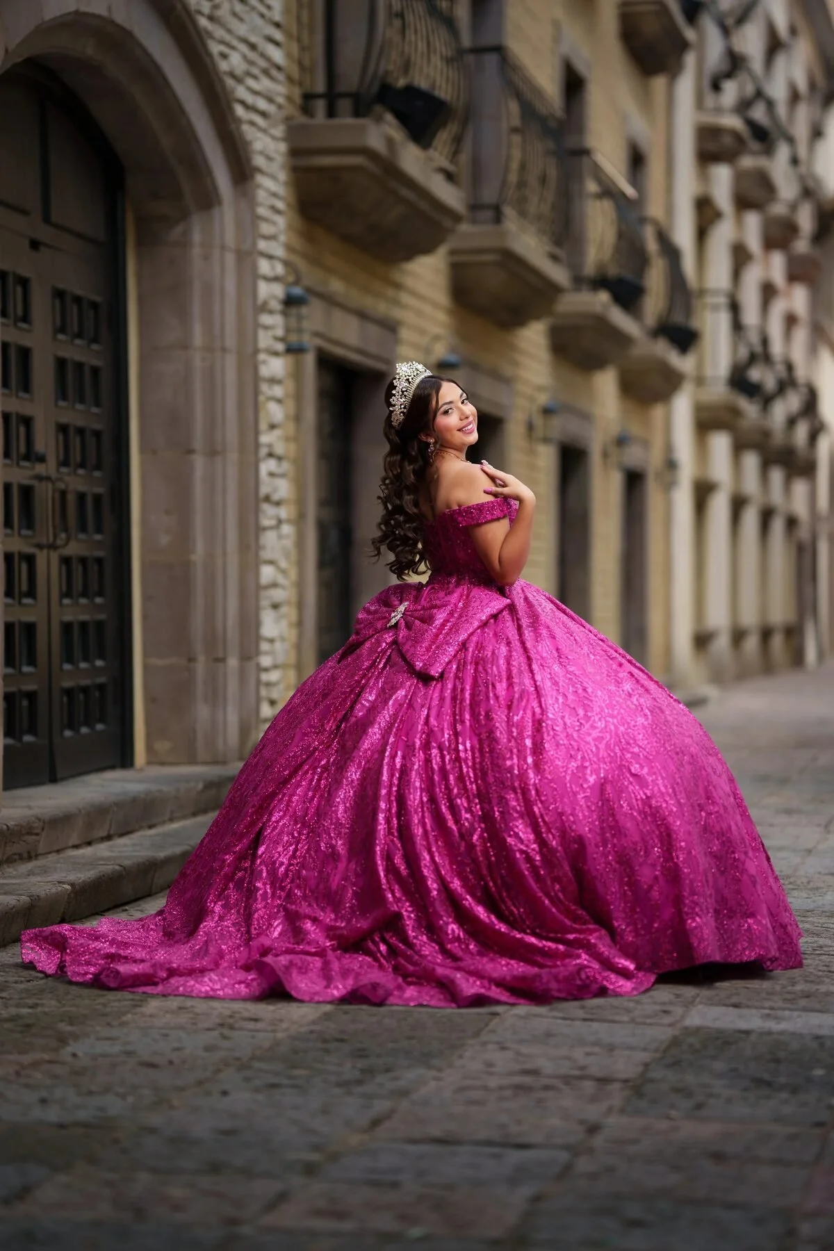 Quinceañera in a fuchsia sequined ball gown on stone steps in Dallas