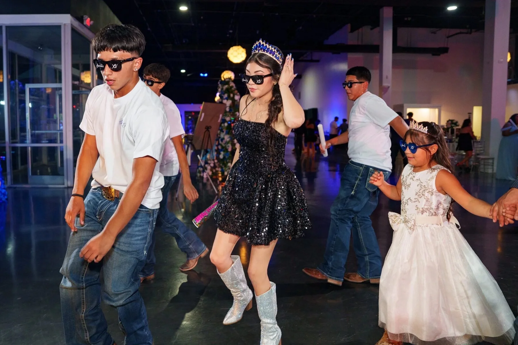 Quinceañera in a black sparkle dress leading a surprise dance at a Dallas reception