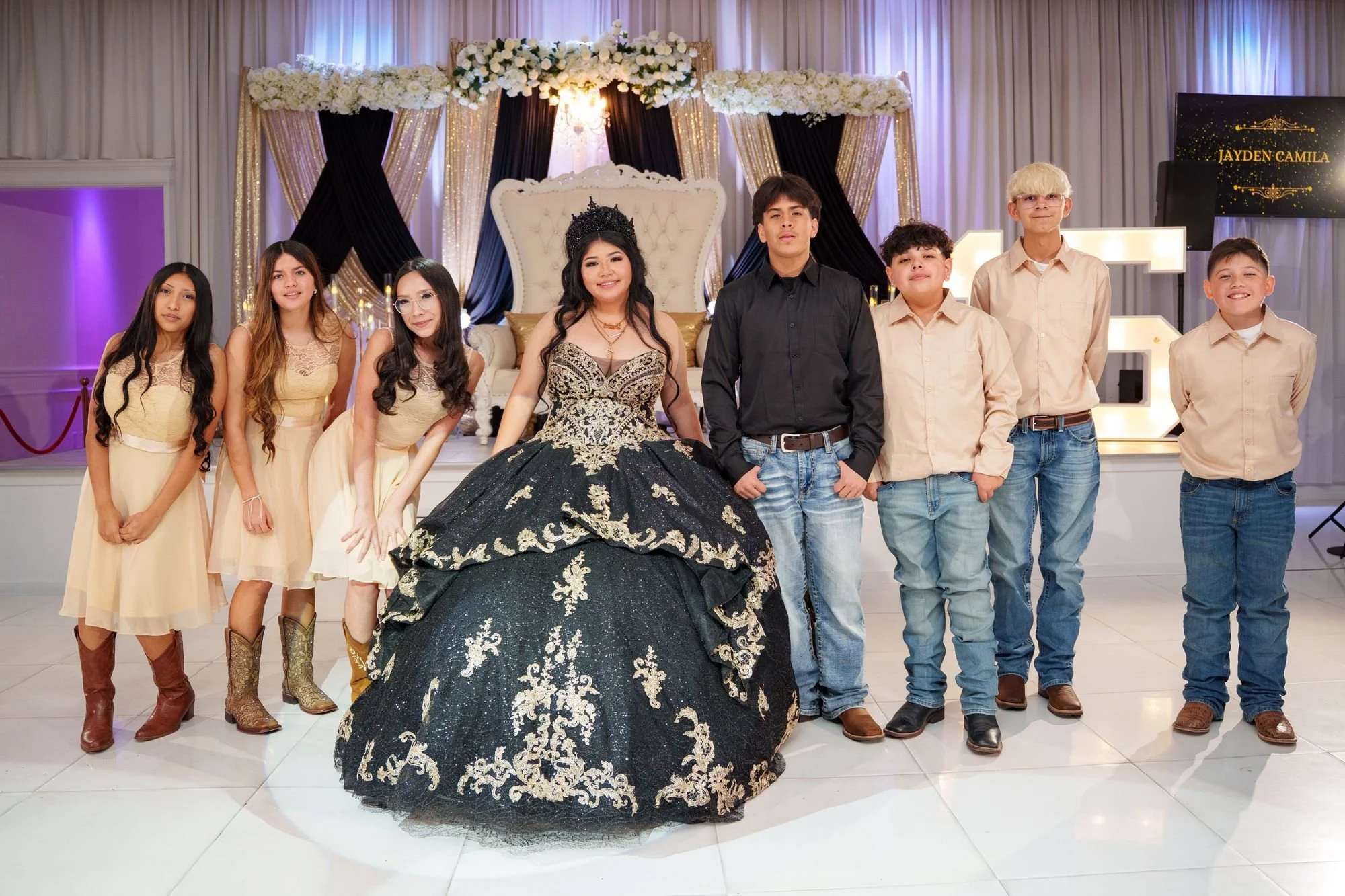 Jayden with her court of damas at the throne stage of her black and gold quinceañera at Luxor Banquet Hall Carrollton