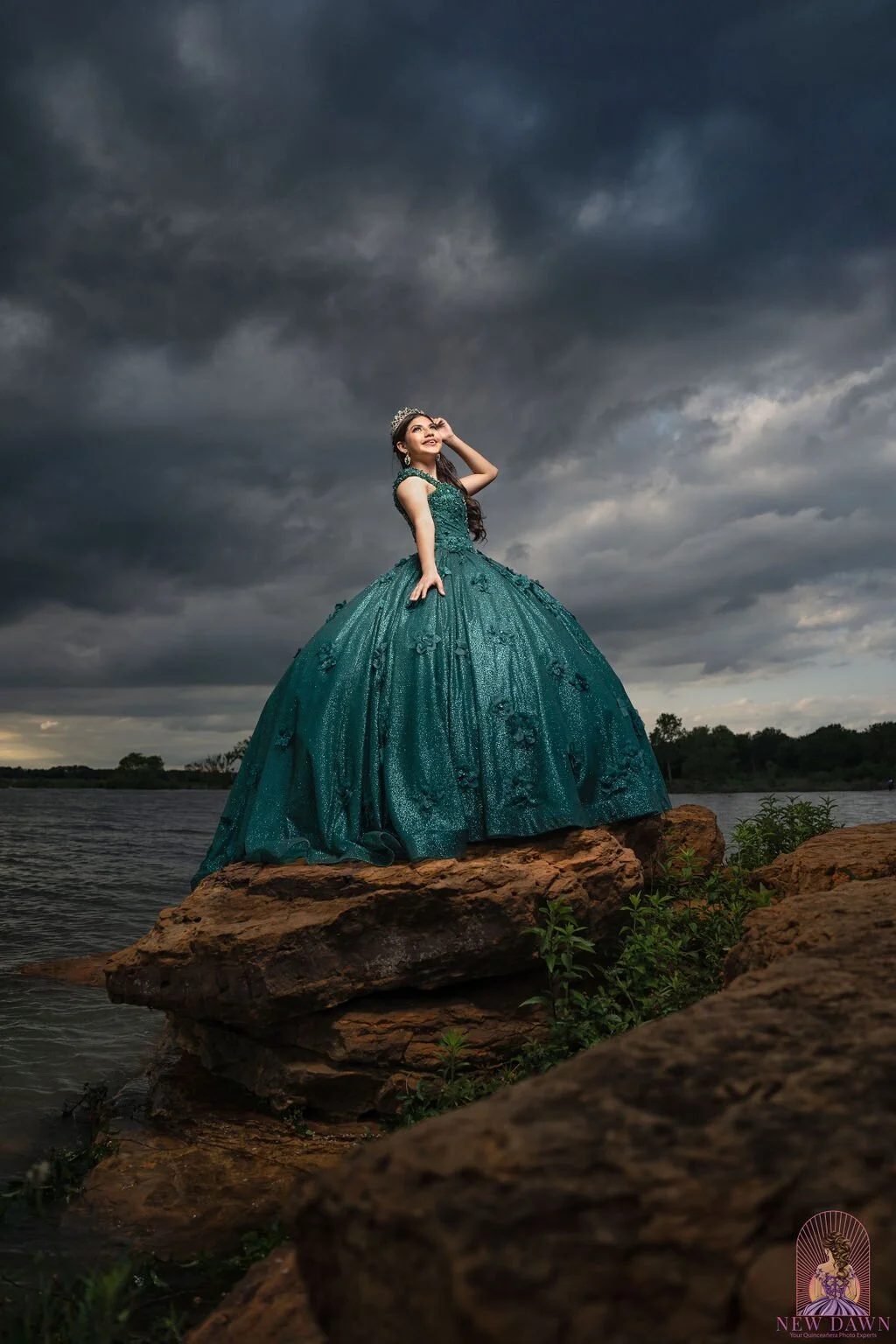  Quinceañera in emerald ball gown gazing skyward as storm clouds gather at Murrell Park in Flower Mound, TX 