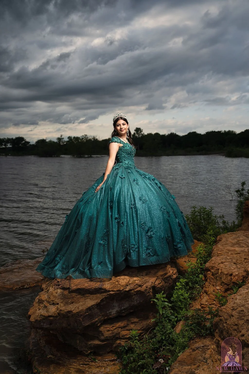  Quinceañera in emerald 3D floral ball gown standing on sandstone shoreline rocks at Murrell Park in Flower Mound, TX 