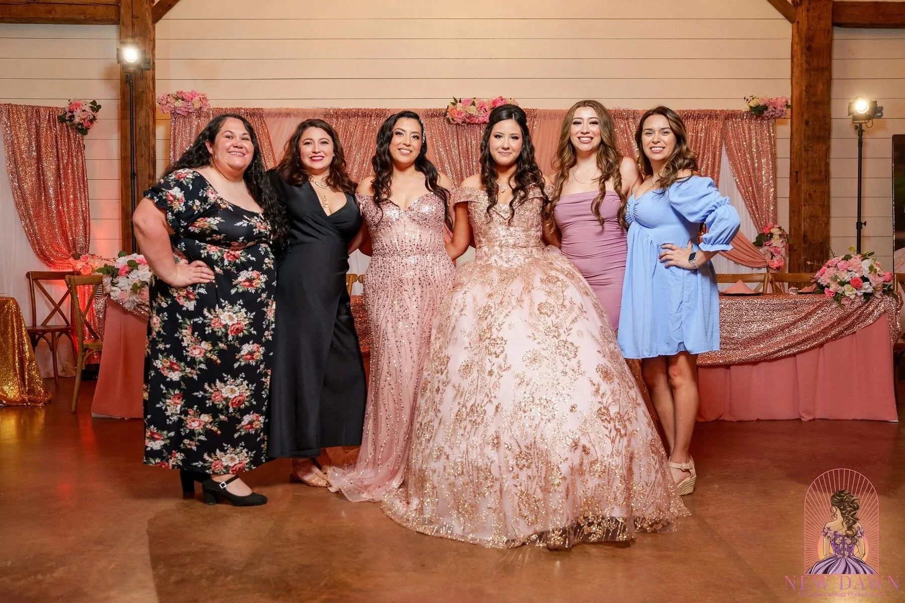 Quinceanera poses with family in front of a rose-gold backdrop at a Texas reception.