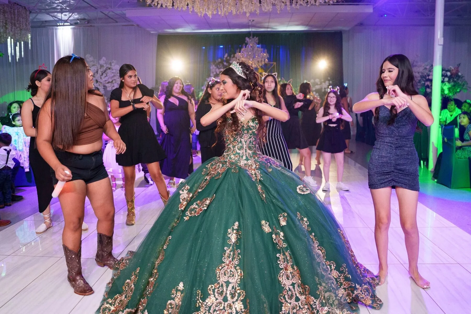 Quinceañera in an emerald charro gown dancing with friends at a DFW reception