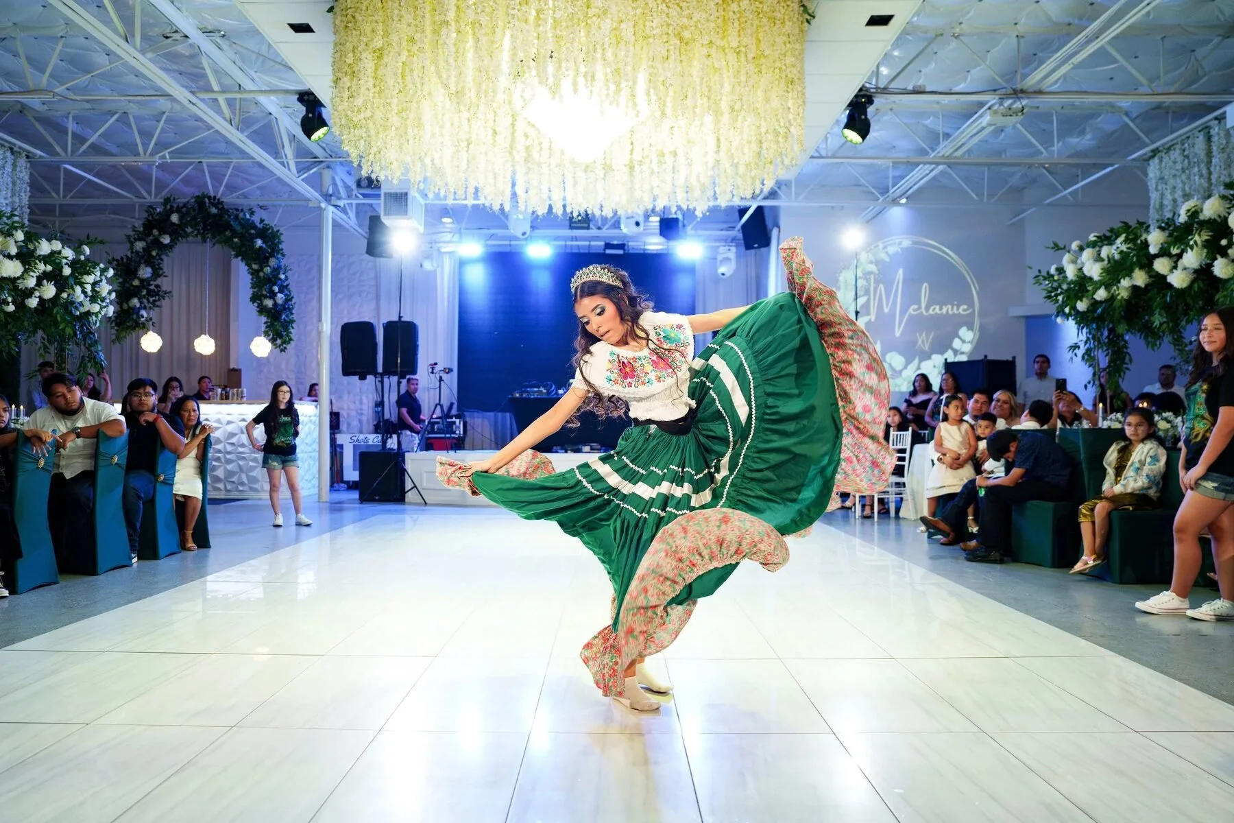 Quinceañera performing a folklórico dance in a green dress at a Dallas reception