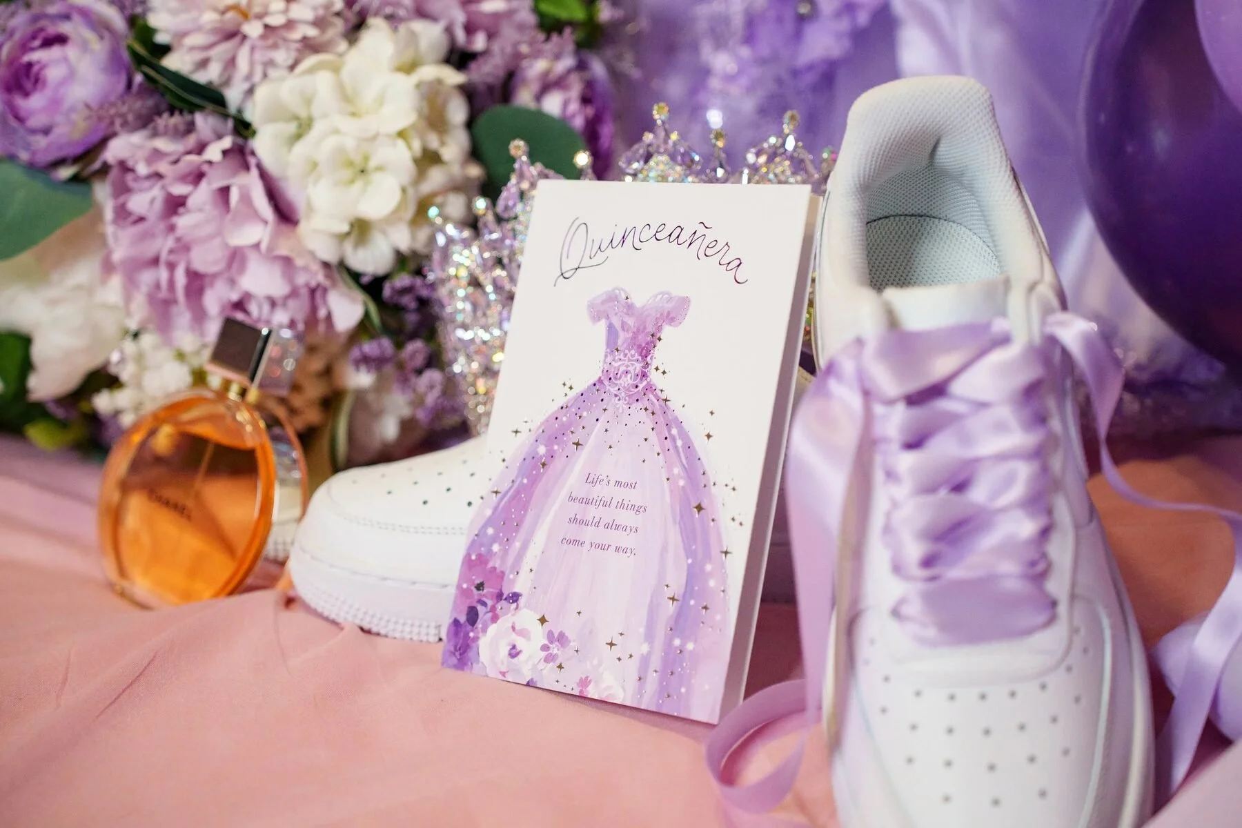 Quinceanera detail photo of a keepsake card, custom sneakers and purple flowers in Dallas.