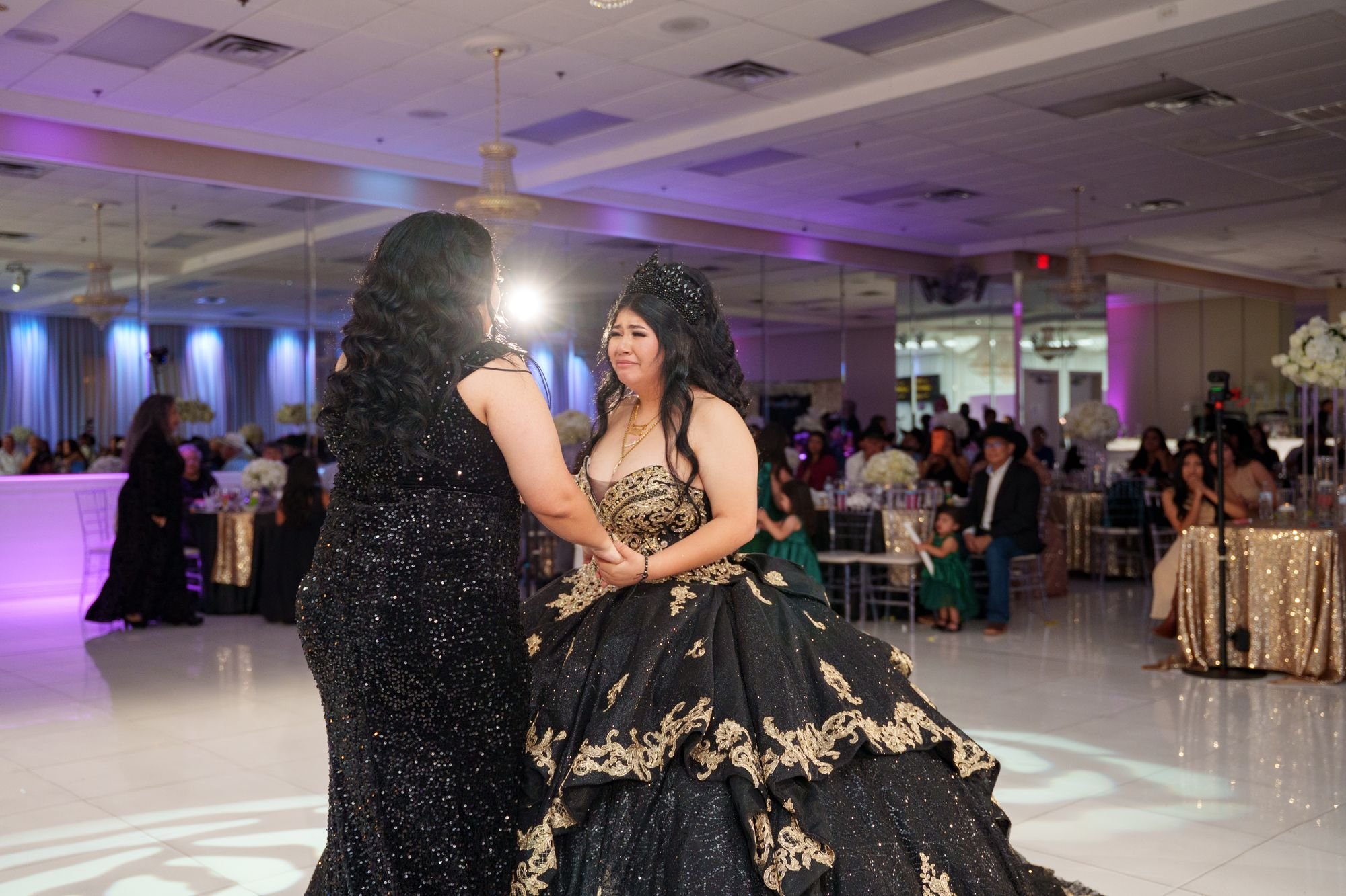 Jayden in black and gold quinceañera ballgown dancing with her mother in black sequin gown during emotional mother-daughter waltz on the marble dance floor at Luxor Banquet Hall Carrollton