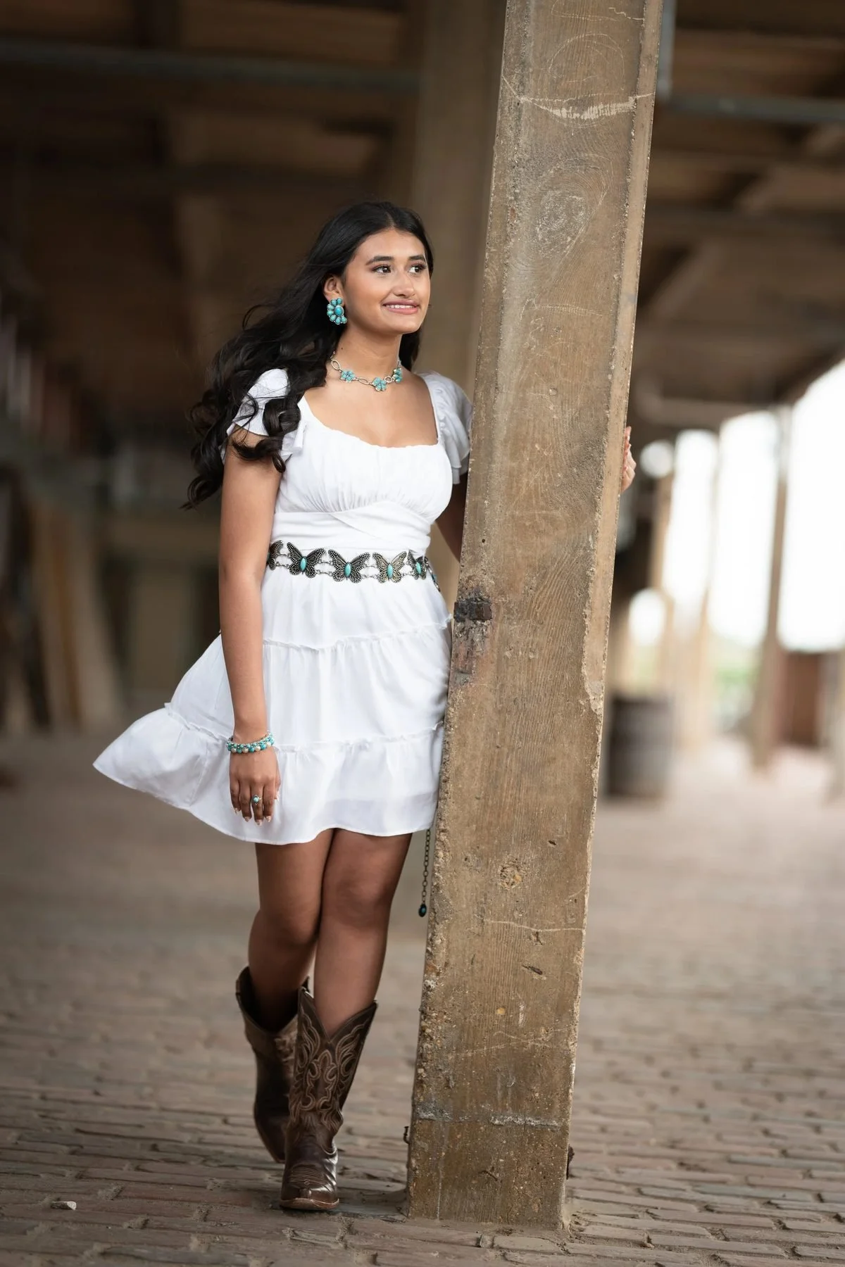 Quinceañera save-the-date in white dress, turquoise butterfly belt, and cowboy boots at the Fort Worth Stockyards