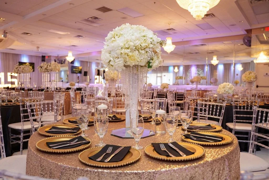 Round guest table with rose gold sequin linen gold beaded chargers black napkins and tall white floral centerpiece with crystal base at Jayden's quinceañera at Luxor Banquet Hall Carrollton