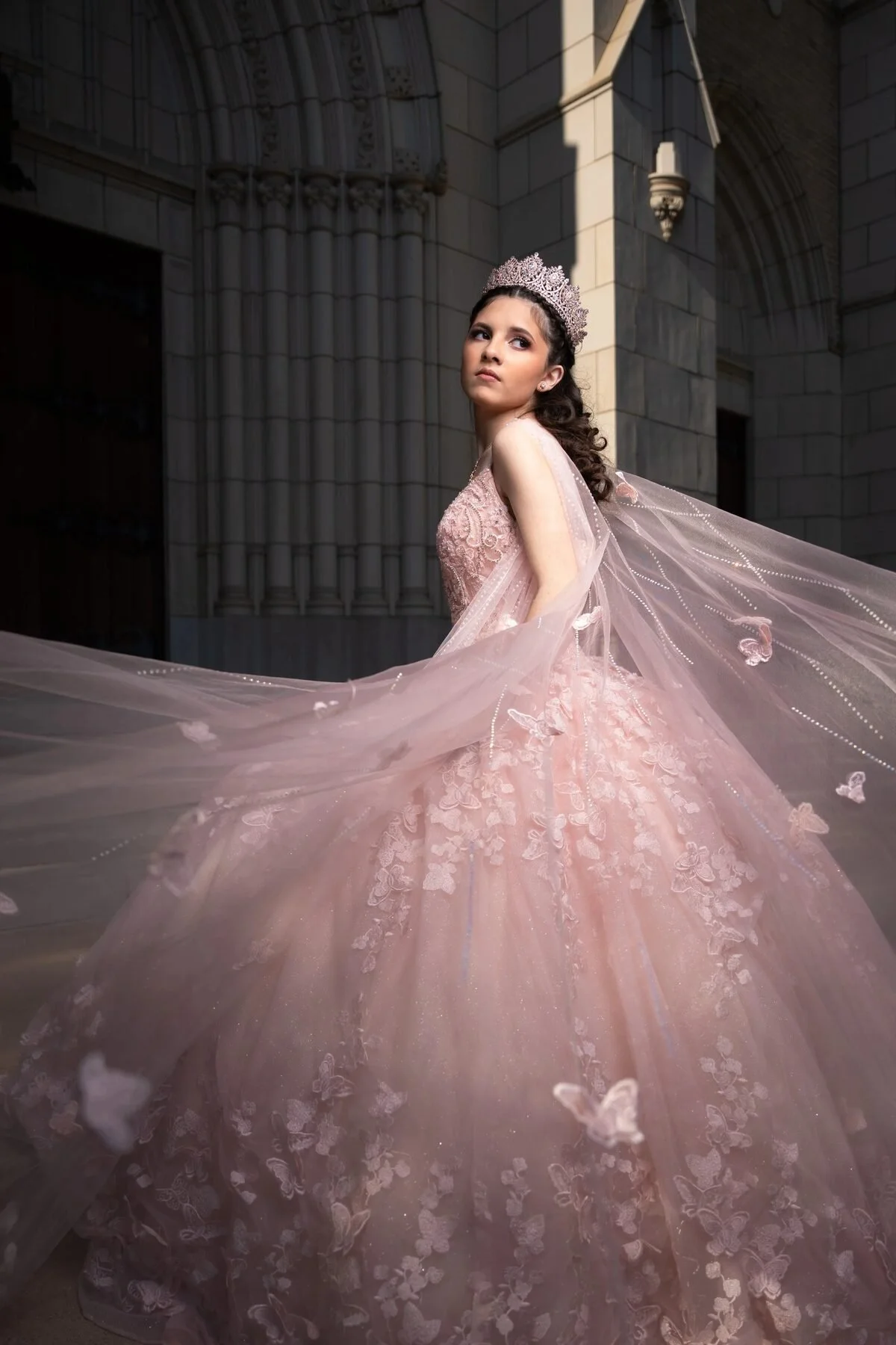Quinceañera in a blush butterfly gown with a flowing cape at a Dallas cathedral
