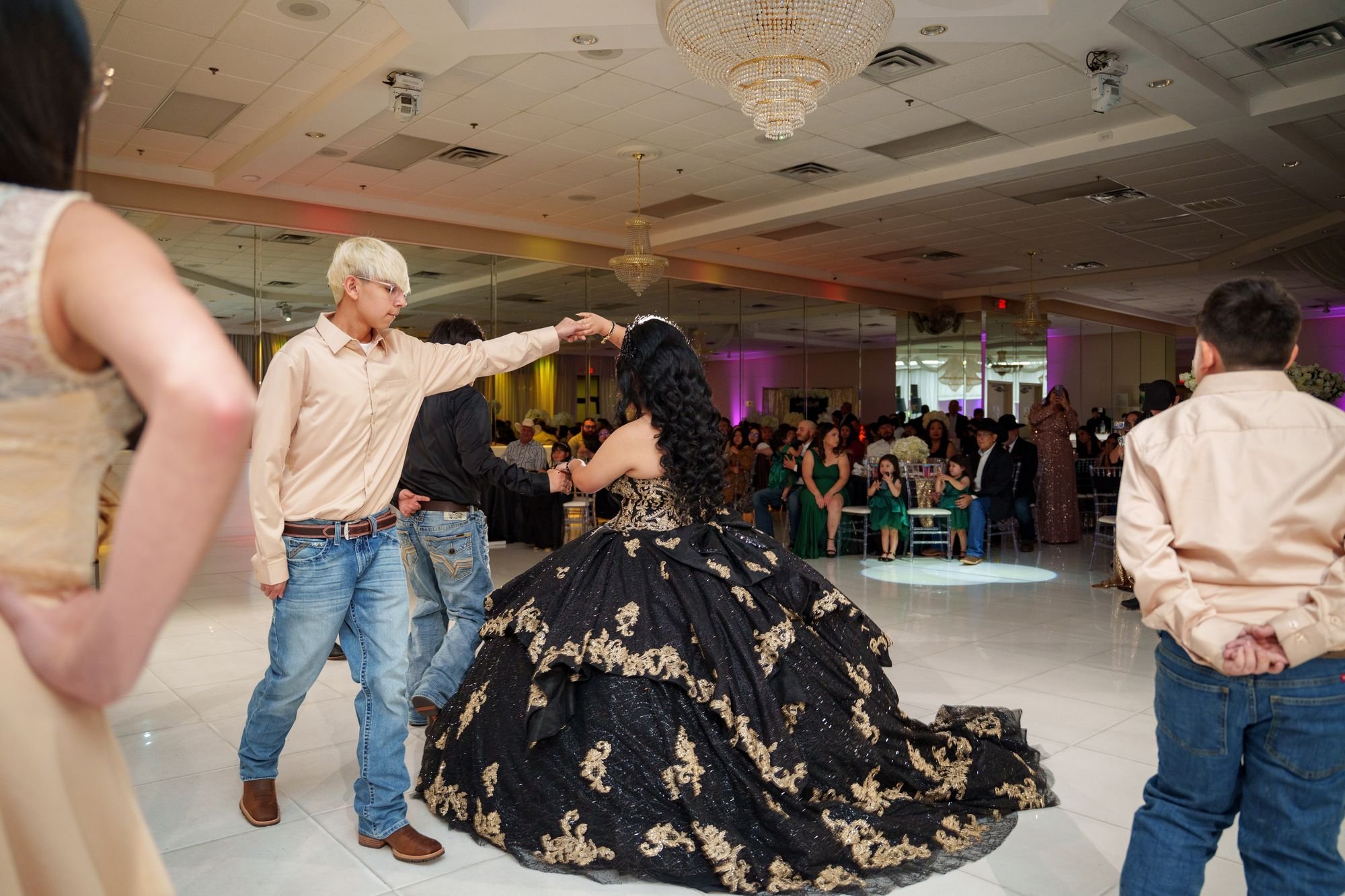 Back view of Jayden's black and gold quinceañera ballgown with cathedral train spread across the white dance floor during her court spin at Luxor Banquet Hall Carrollton