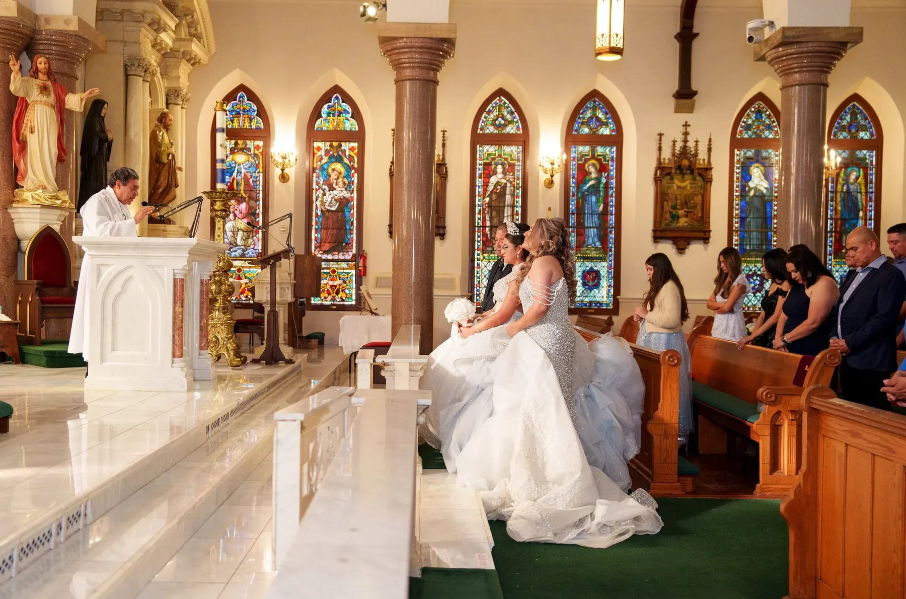 Quinceañera and mother kneel for the church blessing during a Catholic Mass at a Dallas-Fort Worth quinceañera.