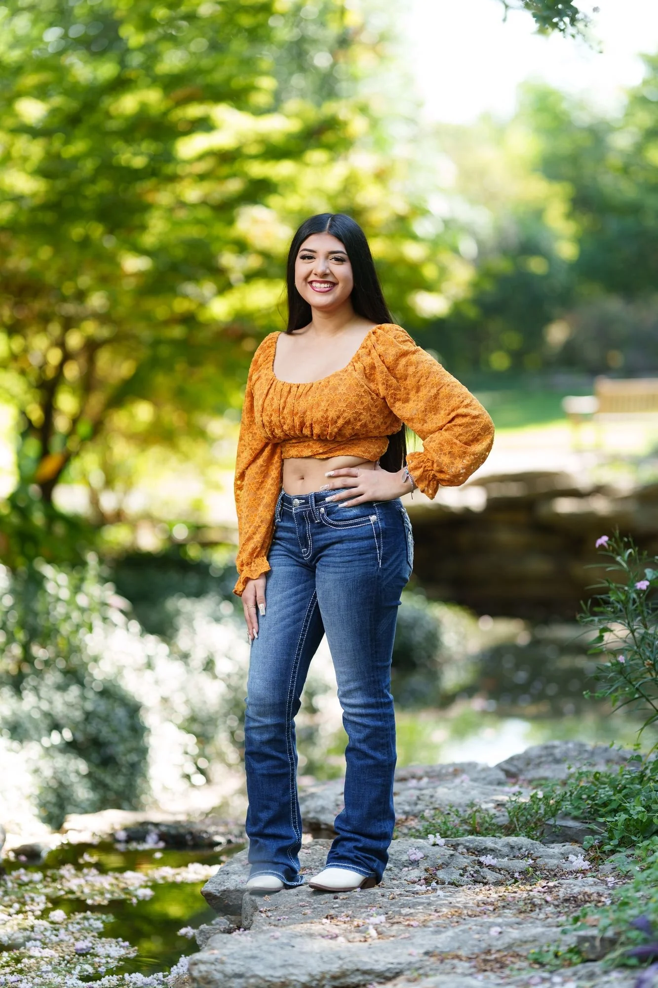 Nevaeh posing on a rock outcrop by the water at Fort Worth Botanic Garden during her boho western Save the Date session