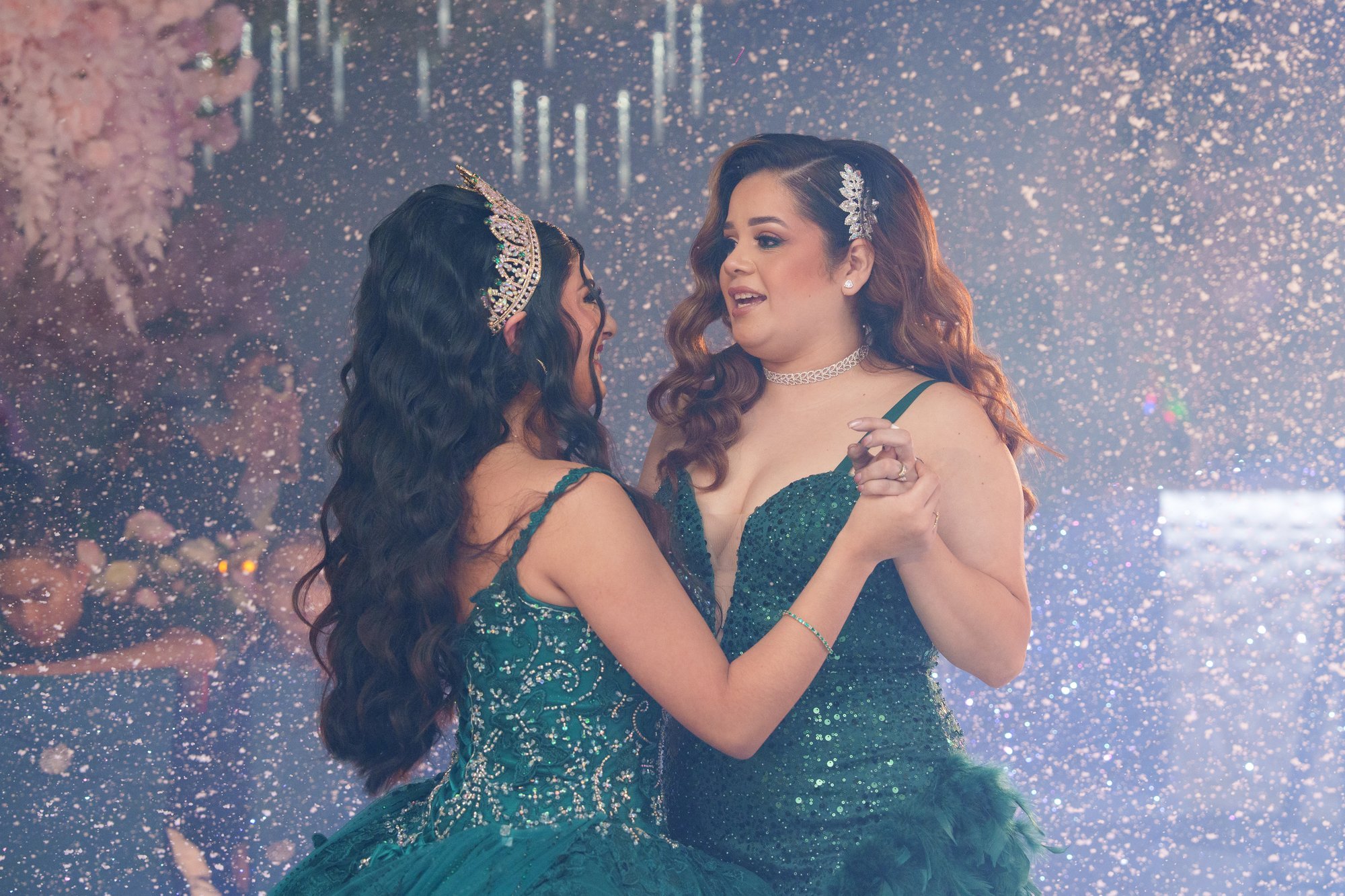 Nevaeh and her mother dancing face-to-face during the mother-daughter dance at her quinceañera, both in emerald green, sparkling overhead light effects on the dance floor