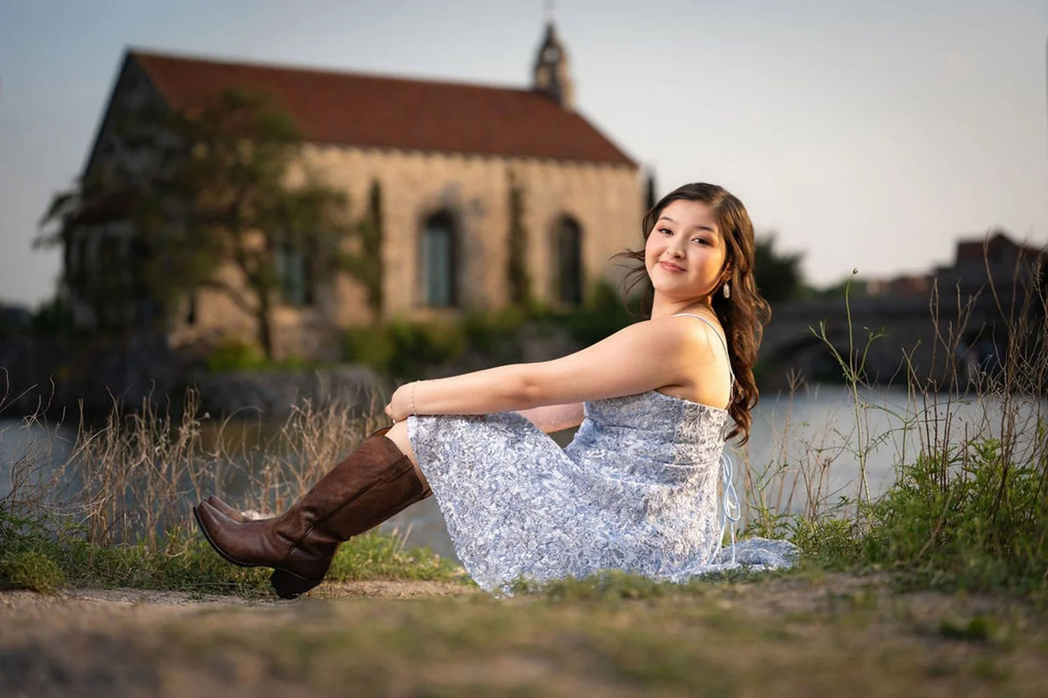 Sesión Save the Date de quinceañera en Adriatica Village en McKinney, vestido corto azul de lentejuelas con botas vaqueras cafés, retrato al atardecer junto al lago por New Dawn Photo