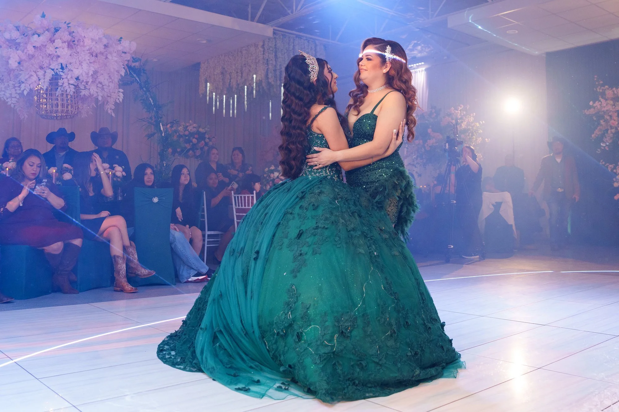 Nevaeh and her mother dancing during the traditional mother-daughter dance, emerald gown on the dance floor with guests watching from candlelit tables