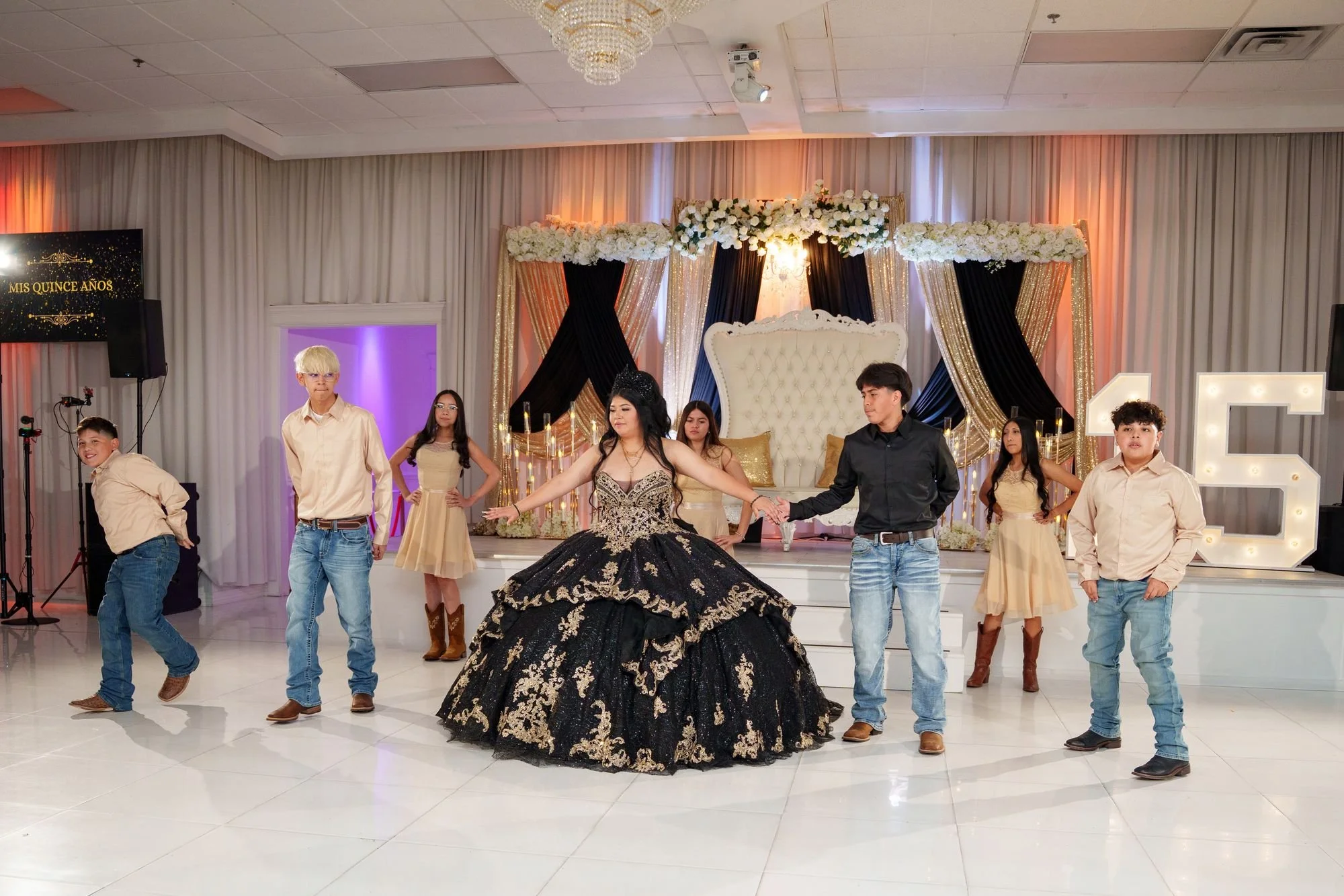 Jayden leading her quinceañera court of three damas in cream chiffon and four chambelanes in cream shirts in a choreographed dance formation on the white dance floor at Luxor Banquet Hall Carrollton TX