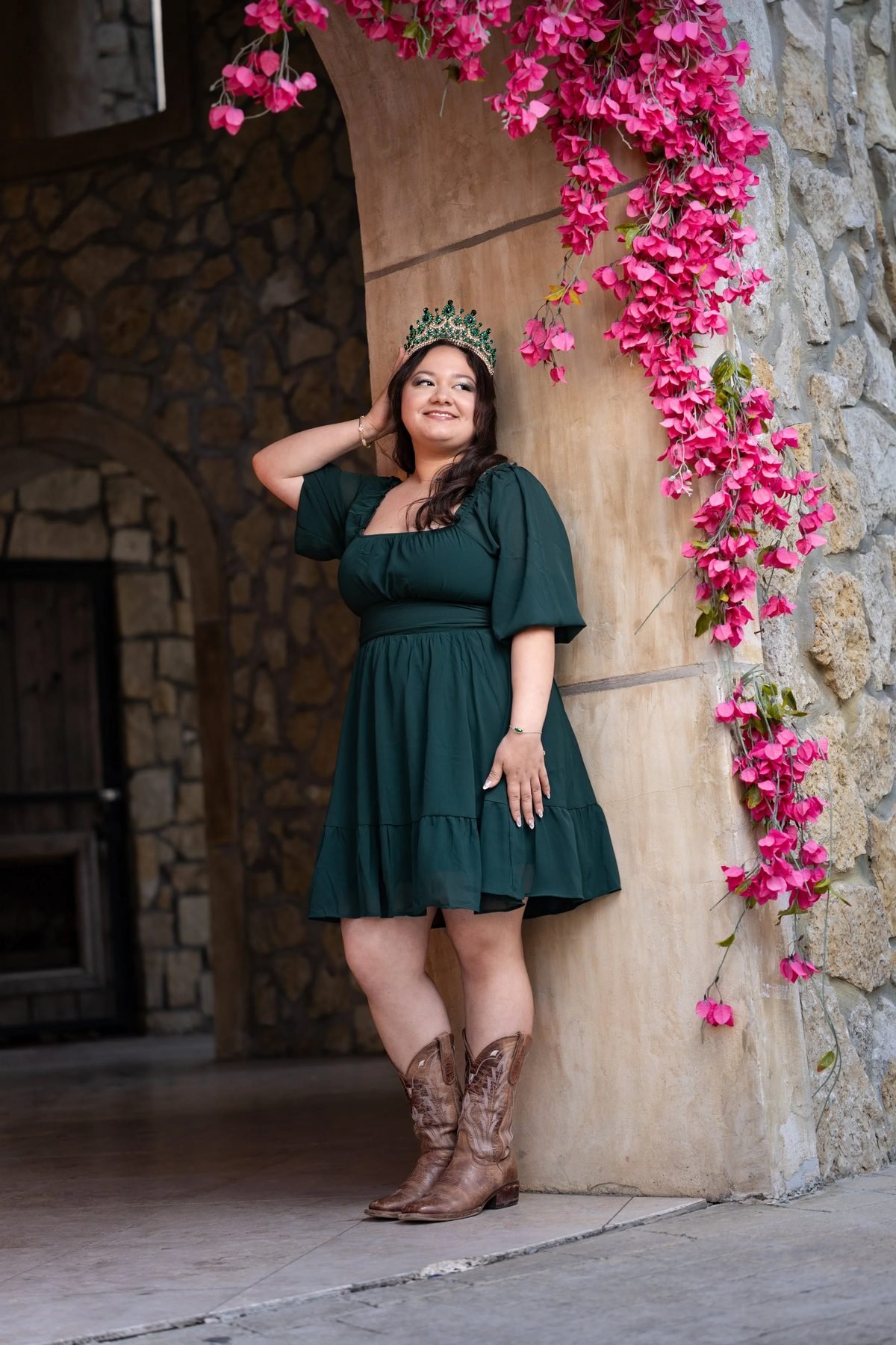 Quinceañera in a green dress and emerald crown beside pink bougainvillea for Dallas save-the-date photos.