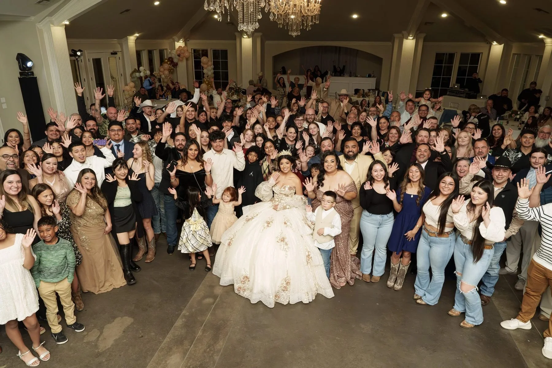 Big family group photo of the quinceañera waving with all her guests at her DFW reception