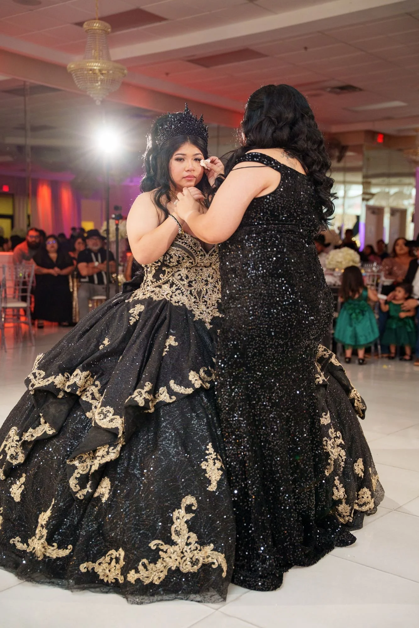 Jayden's mother in black sequin gown comforting her during emotional moment of mother-daughter waltz with tears at her quinceañera at Luxor Banquet Hall Carrollton TX