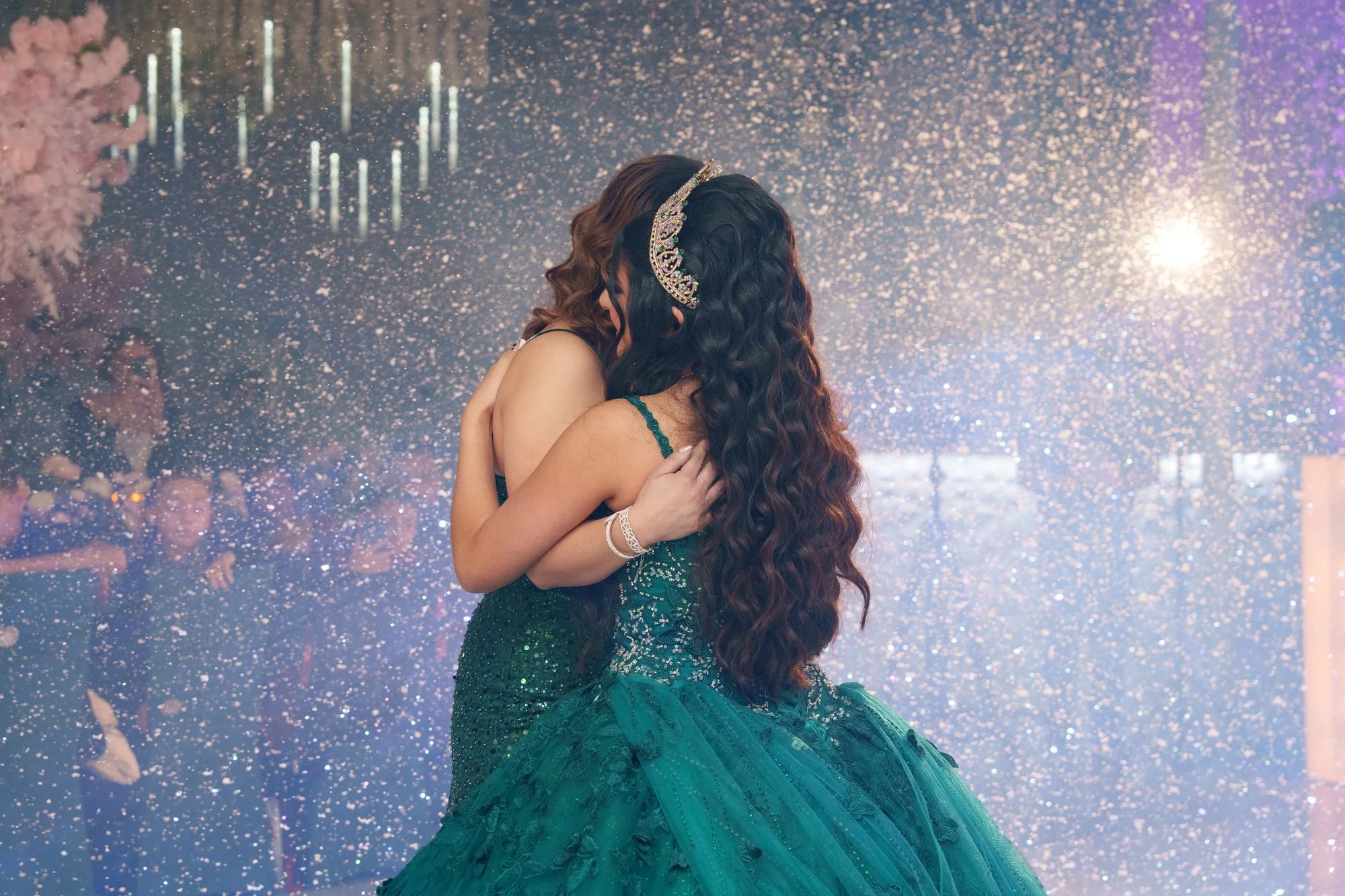 Nevaeh embracing her mother during the traditional crowning moment, overhead light streaming down like falling confetti
