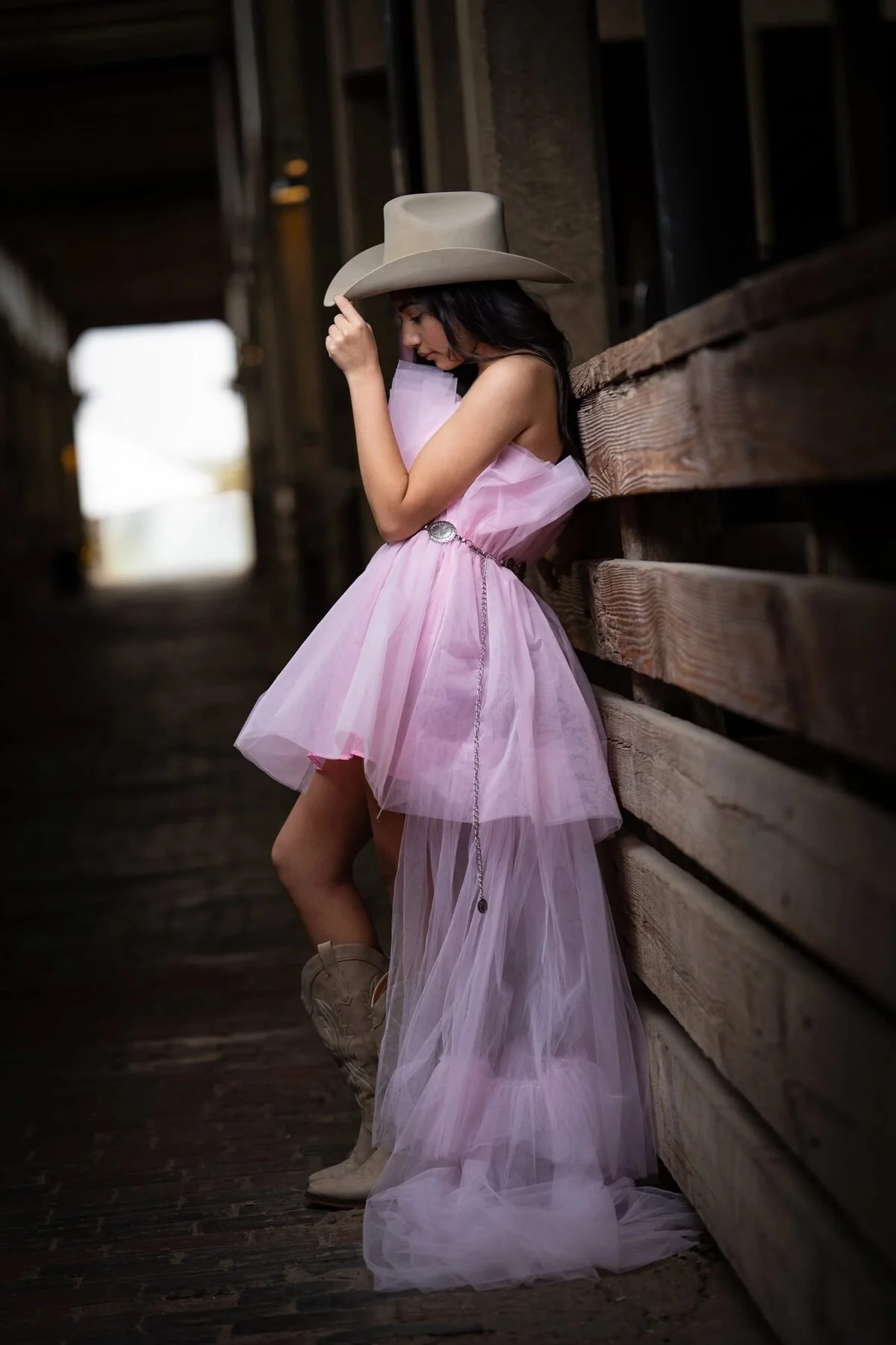 Quinceañera in a pink tulle dress and cowboy hat in a Texas barn during a Save the Date shoot
