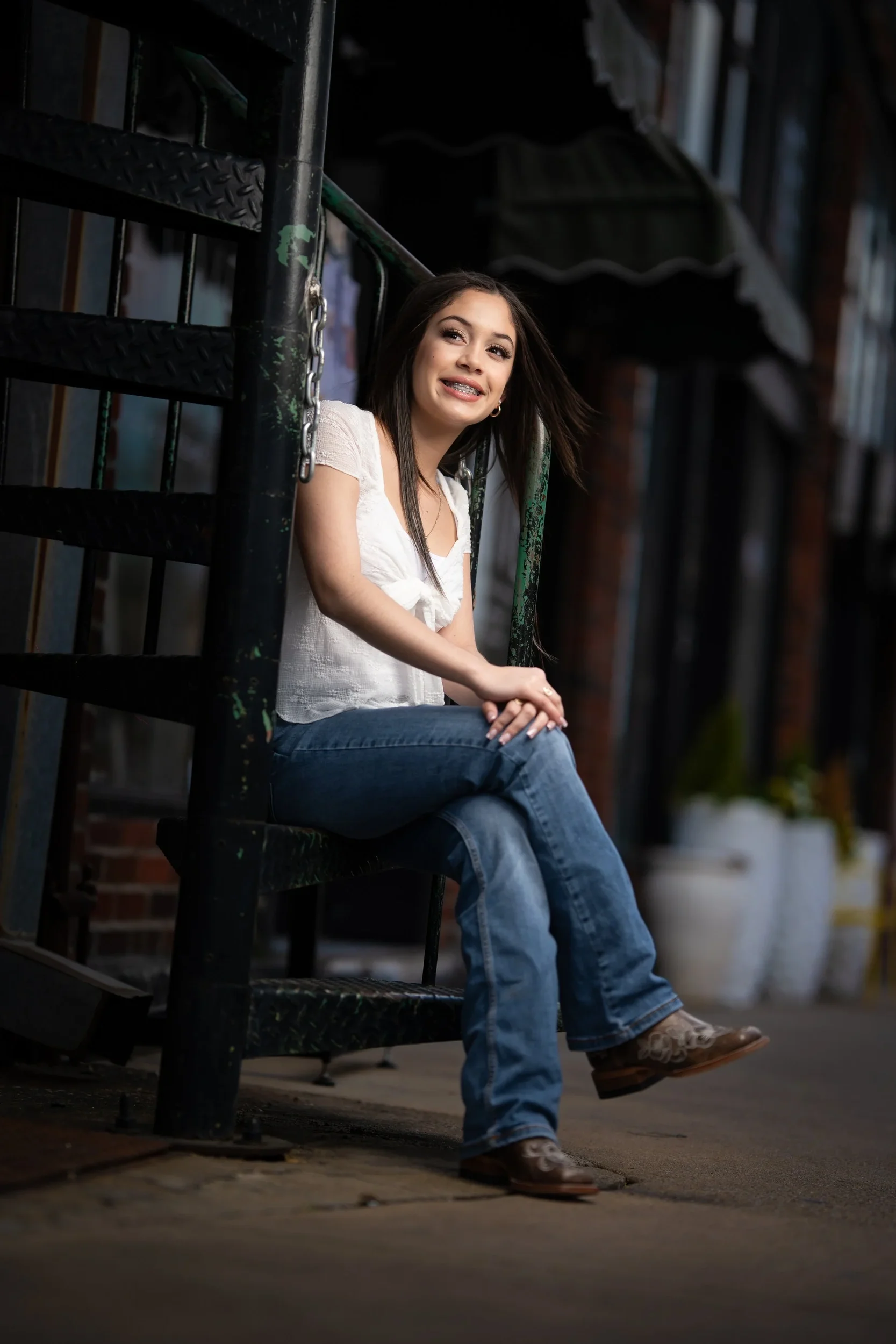 Quinceanera in jeans and cowboy boots poses downtown for a DFW Save the Date session.