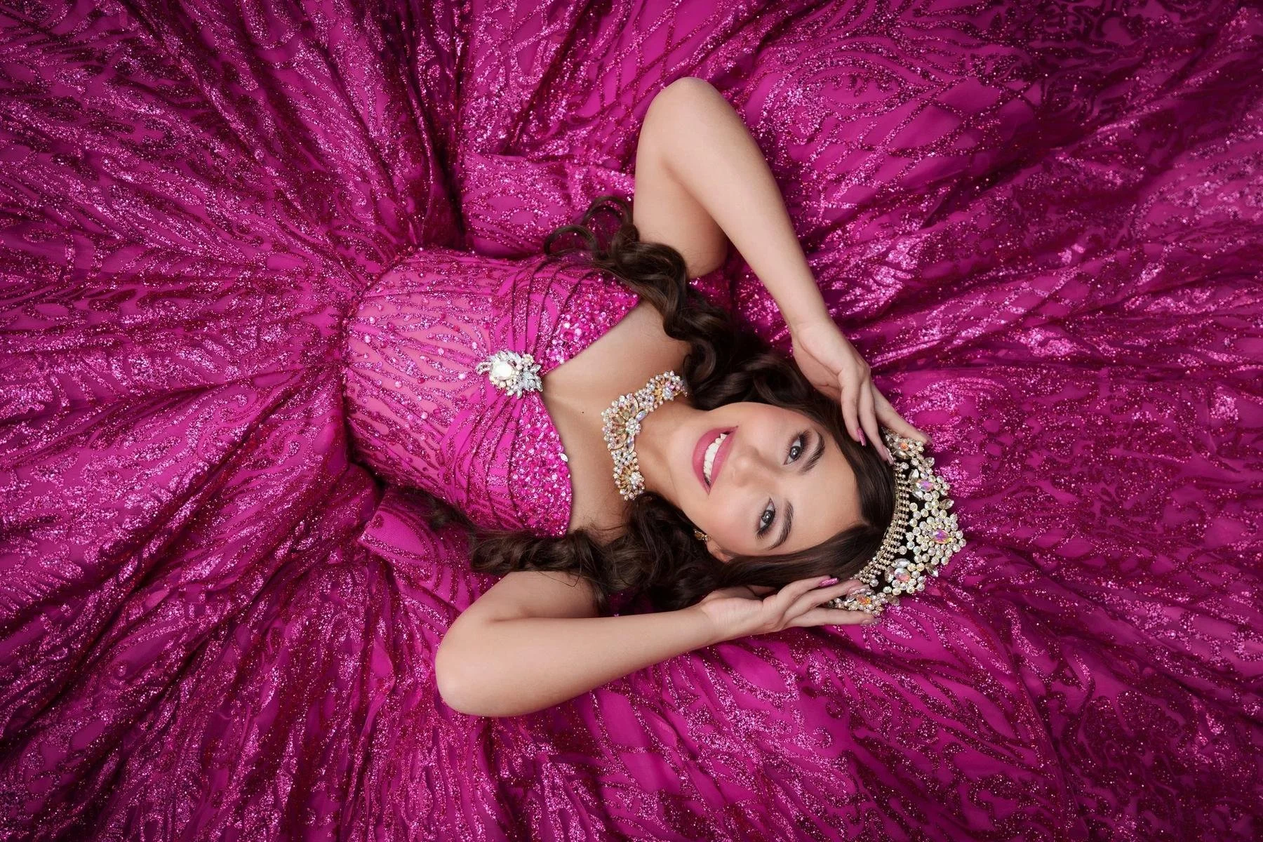 Quinceañera in a magenta glitter ball gown posing for an overhead portrait in the Dallas-Fort Worth area.