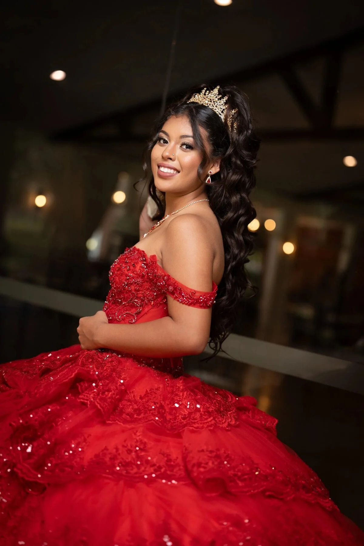Quinceañera in a red tiered gown and gold crown at an elegant Fort Worth venue
