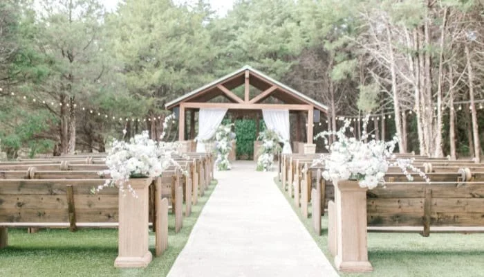 Espacio ceremonial al aire libre entre árboles con pérgola de madera en Hidden Creek Events en Heath, Texas