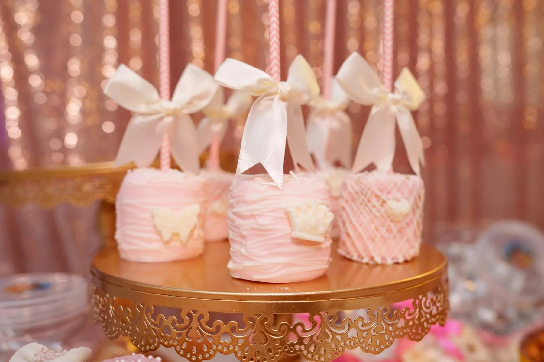 Pink marshmallow pops on a gold stand decorate a Dallas quinceanera dessert table.