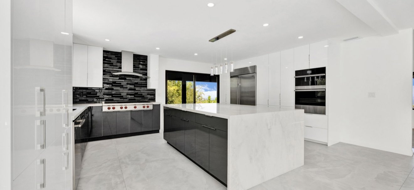 Kitchen with white upper cabinets, dark lower cabinets and an island.