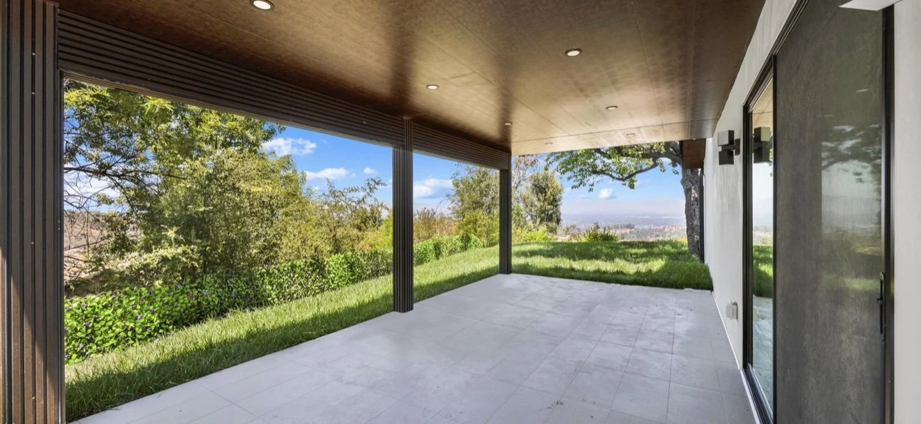 Covered patio with wood flooring and a light-colored exterior wall.