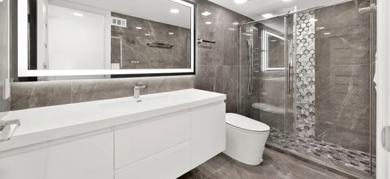 Bathroom with a glass shower, floating vanity and illuminated mirror.