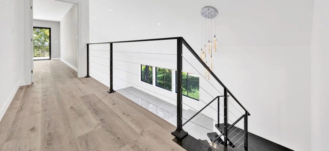 Interior stair landing with wood flooring and a dark railing.