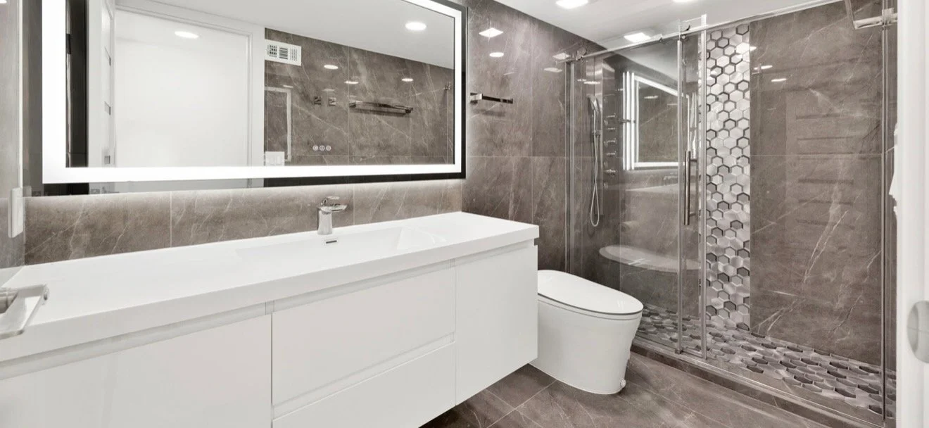 Bathroom with a glass shower, floating white vanity and illuminated mirror