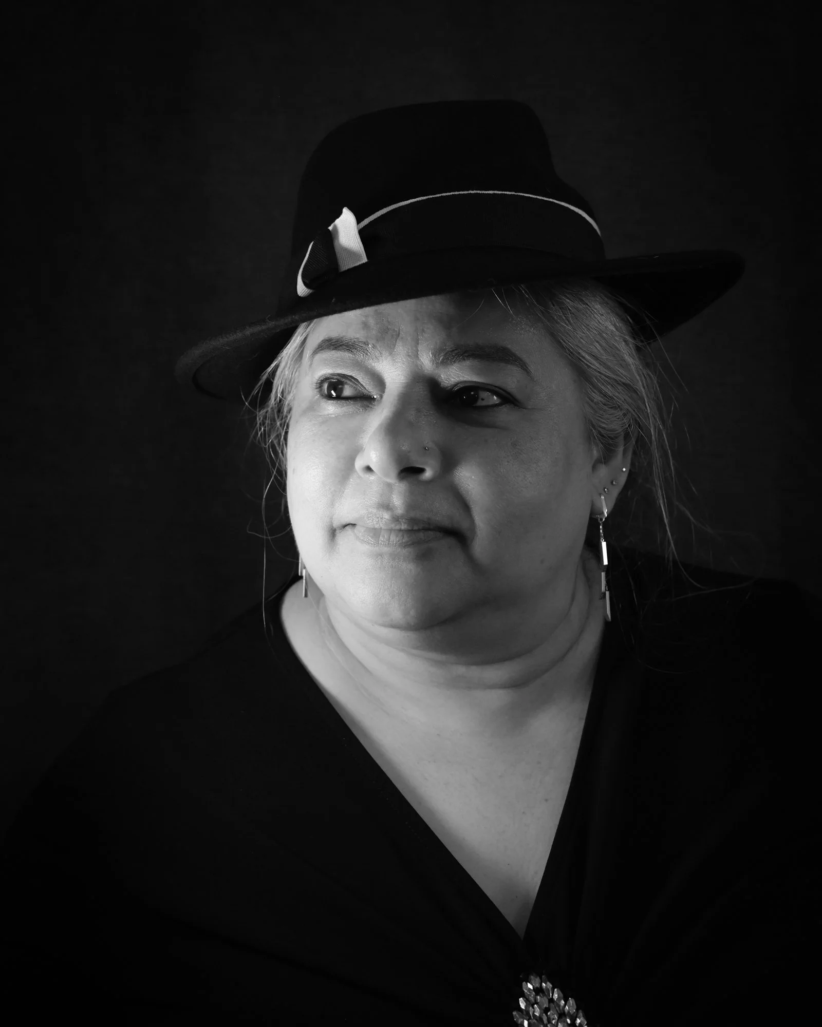 Black and white portrait of a woman wearing a wide-brimmed hat with a ribbon, looking to her left.