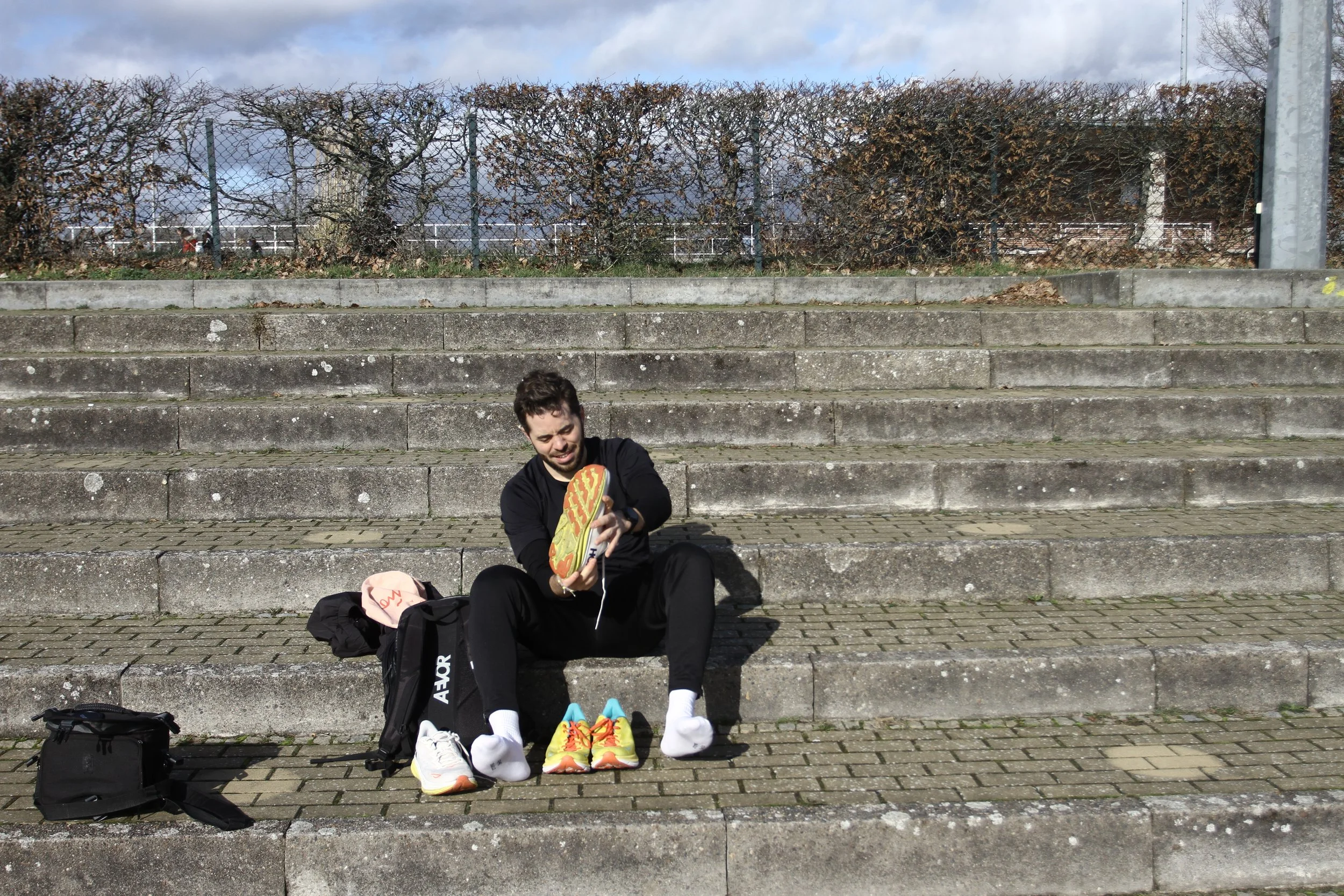 Ferdi Nees sitzt auf Treppenstufen und hält Laufschuhe in der Hand