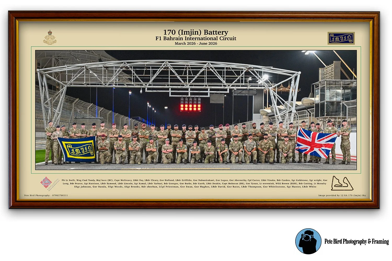 Group of soldiers in military uniforms standing on a racetrack at night, some holding flags, under a large overhead structure, with text describing their deployment at Bahrain International Circuit from March to June 2026.