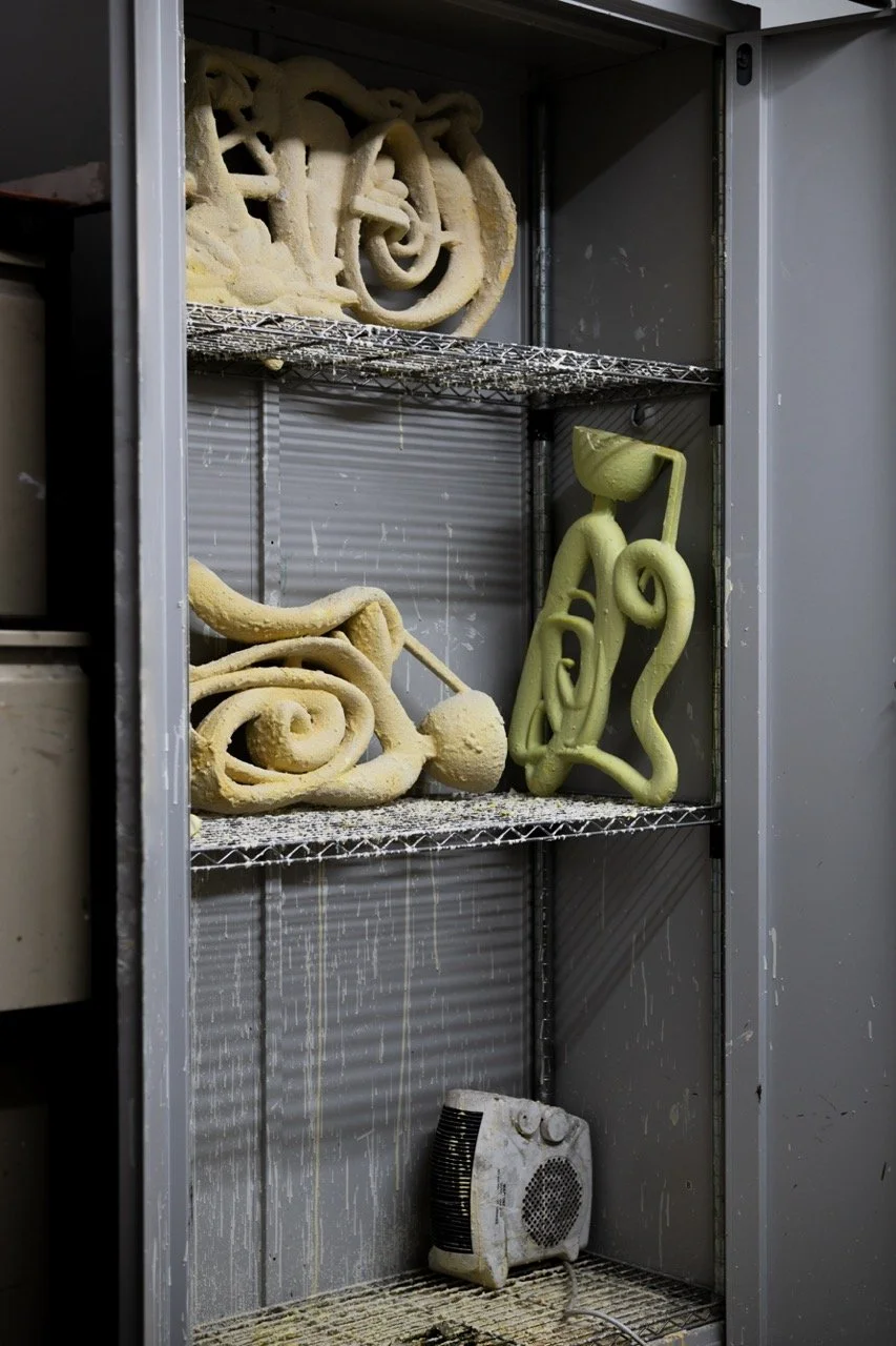 Metal storage cabinet with foam sculpture art pieces on shelves and a small heater at the bottom