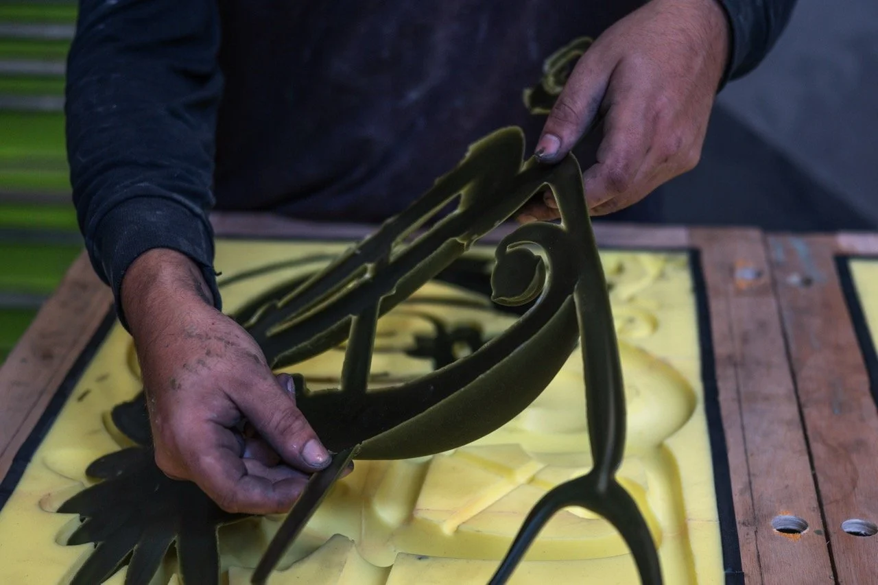 Hands working with black and yellow silicone molds on a yellow surface, possibly making or examining a mold.