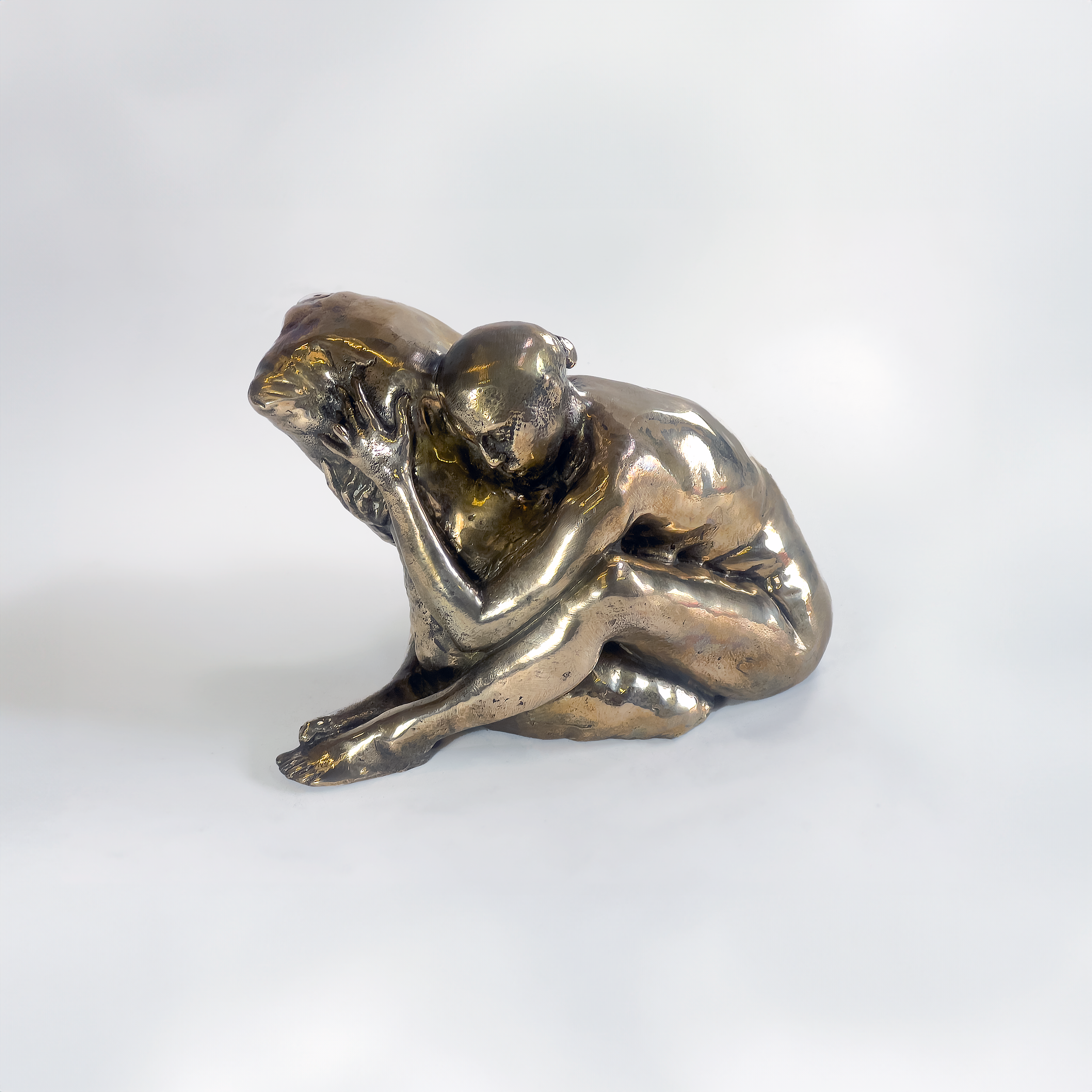 A bronze sculpture of a seated woman with her head resting on her hand, appearing to be in a contemplative pose.
